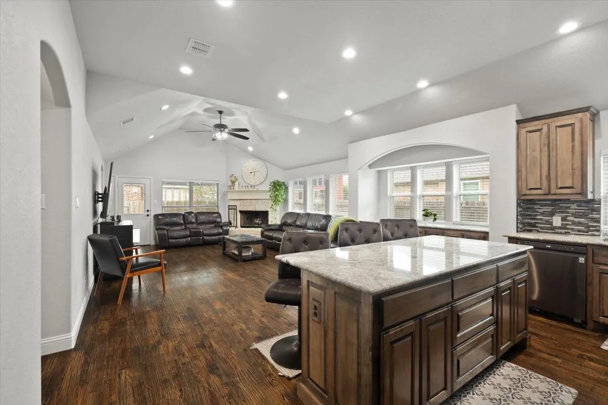 Kitchen with a kitchen bar, a kitchen island, light stone countertops, healthy amount of natural light, and recessed lighting