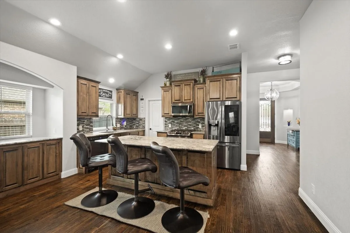 Kitchen with a breakfast bar, stainless steel appliances, a kitchen island, wood finish cabinets, and dark wood finished floors