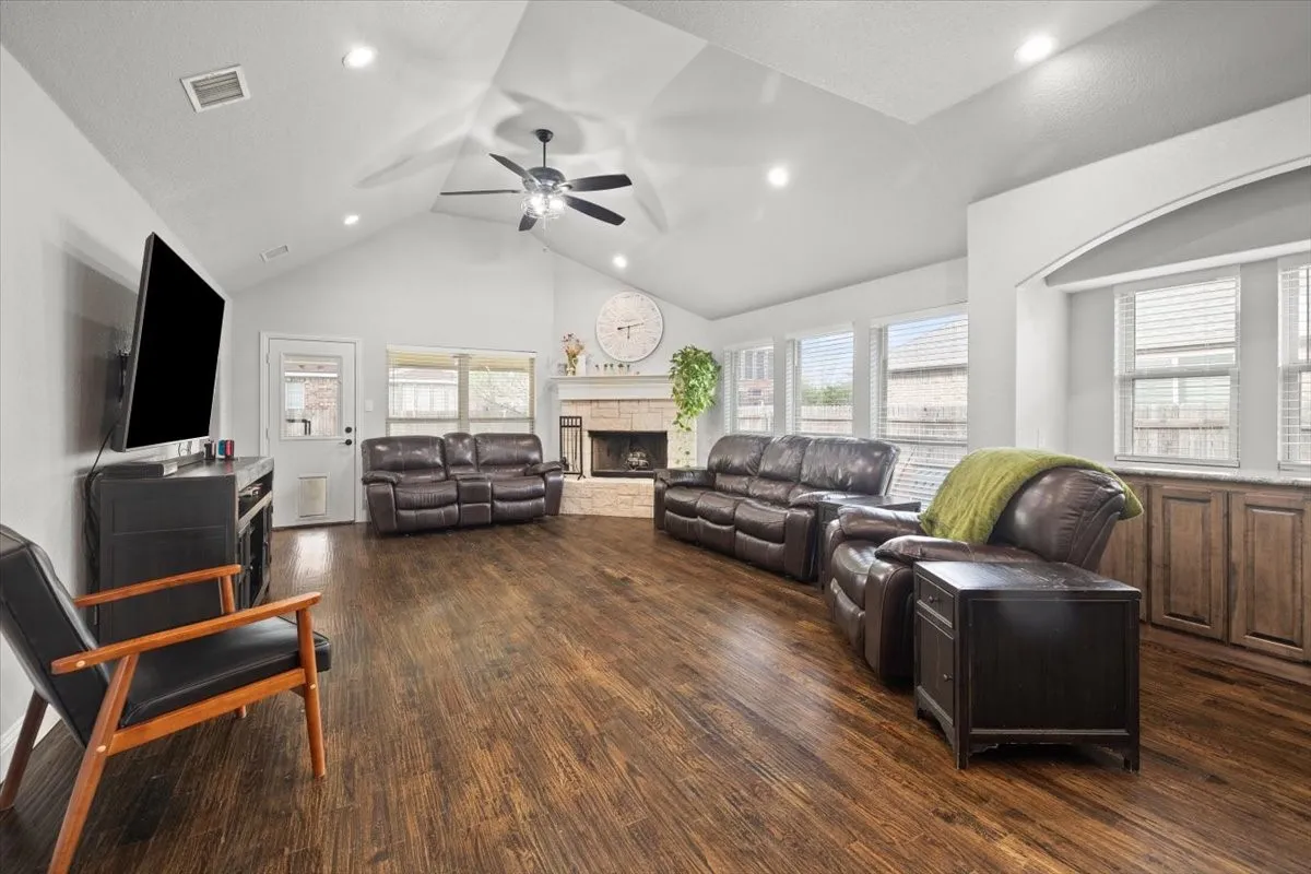 Living room with a ceiling fan, dark wood-style flooring, a fireplace, a high ceiling, and recessed lighting