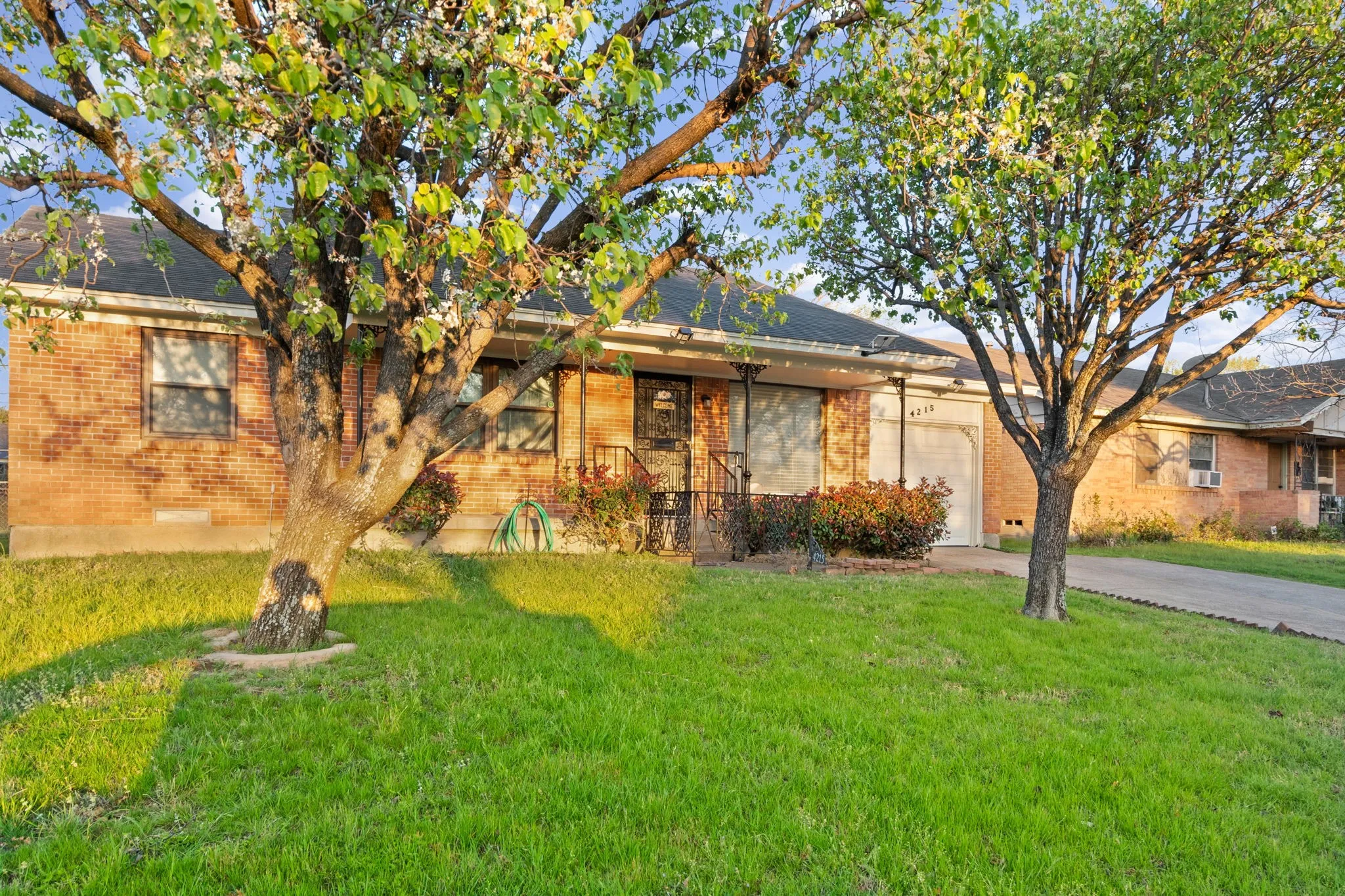 View of front of house featuring brick siding, a garage, a front yard, and concrete driveway