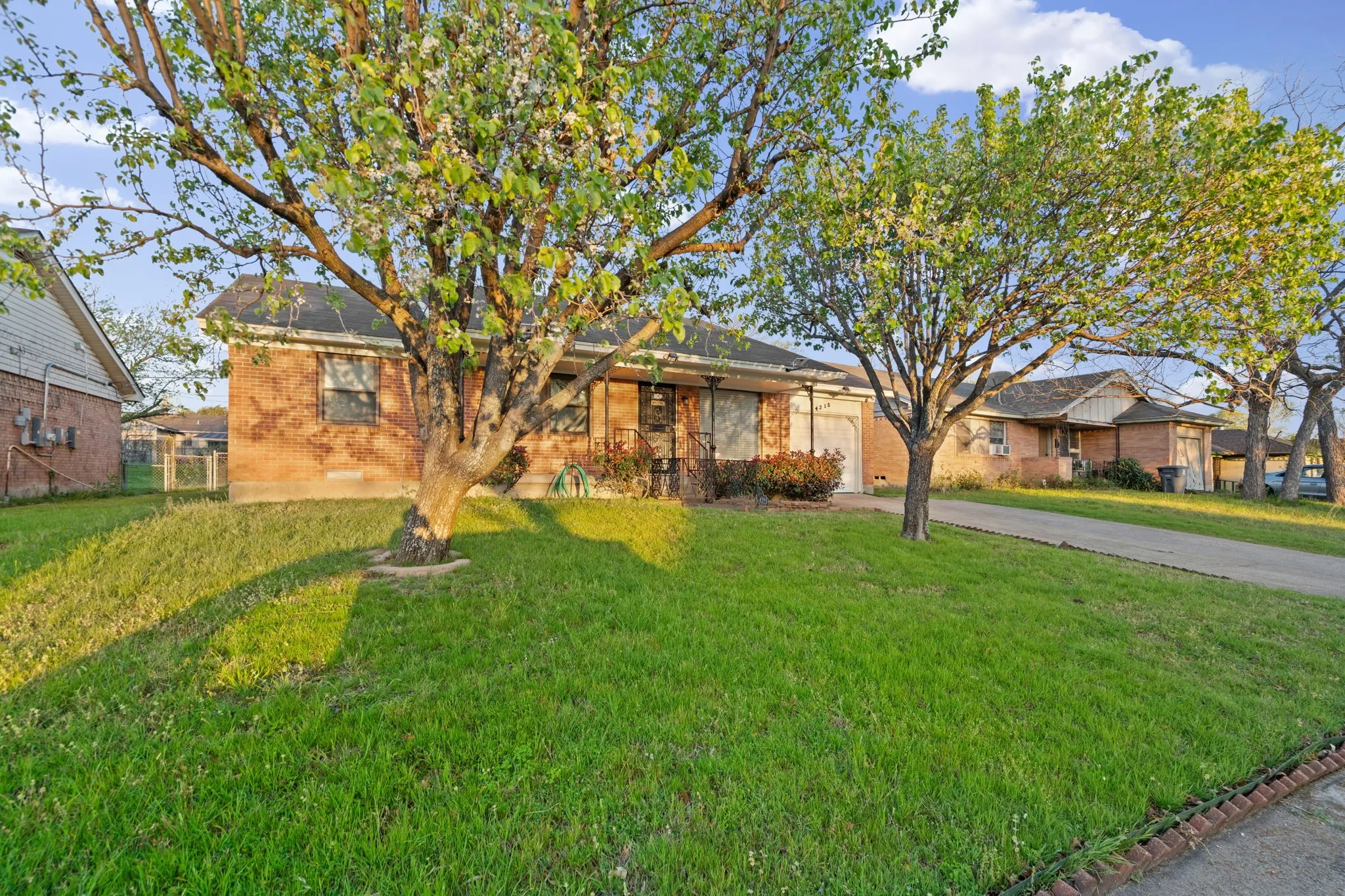Ranch-style home featuring a front yard, concrete driveway, brick siding, and an attached garage