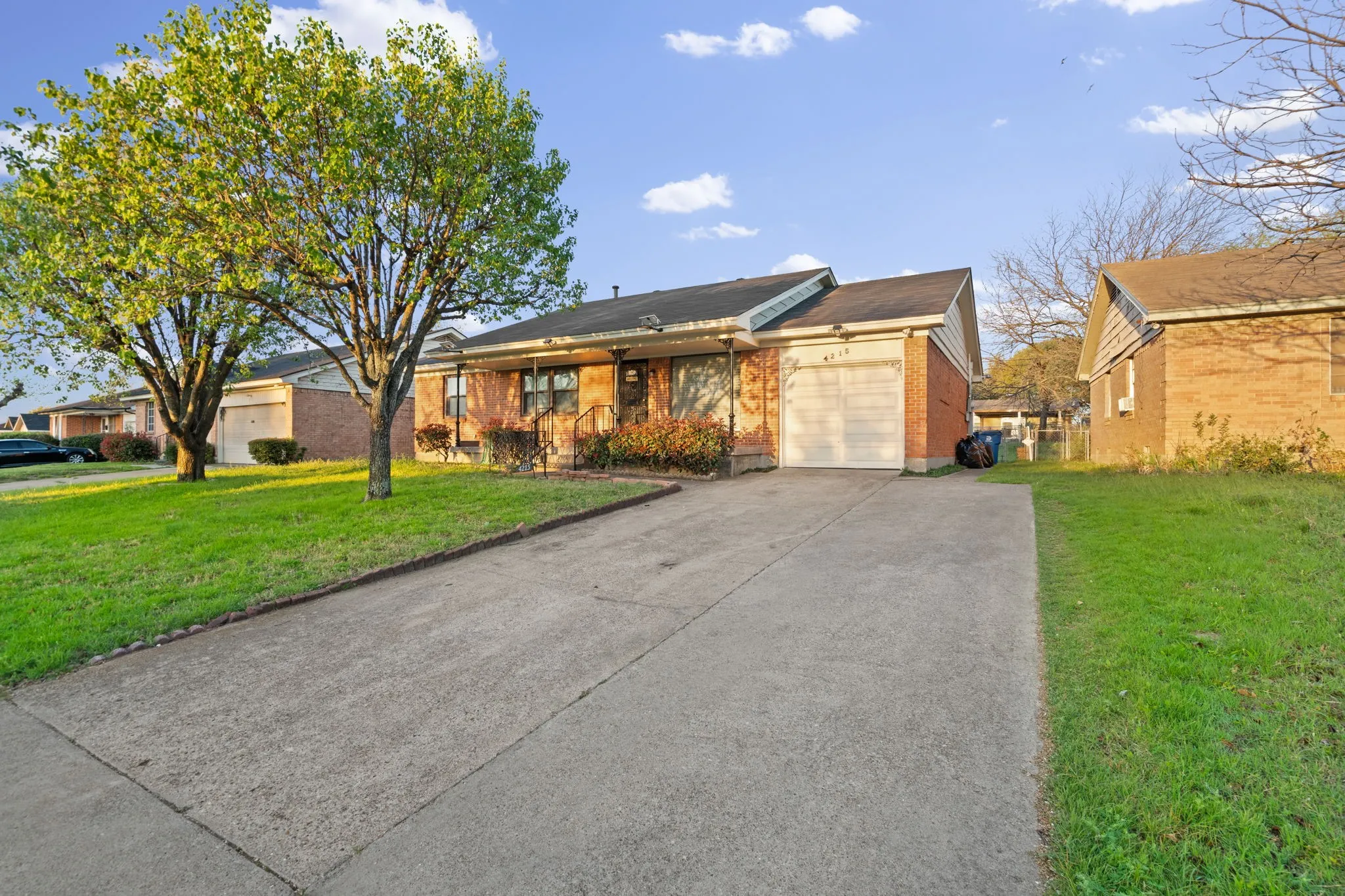 Ranch-style home with a front lawn, a garage, driveway, and brick siding