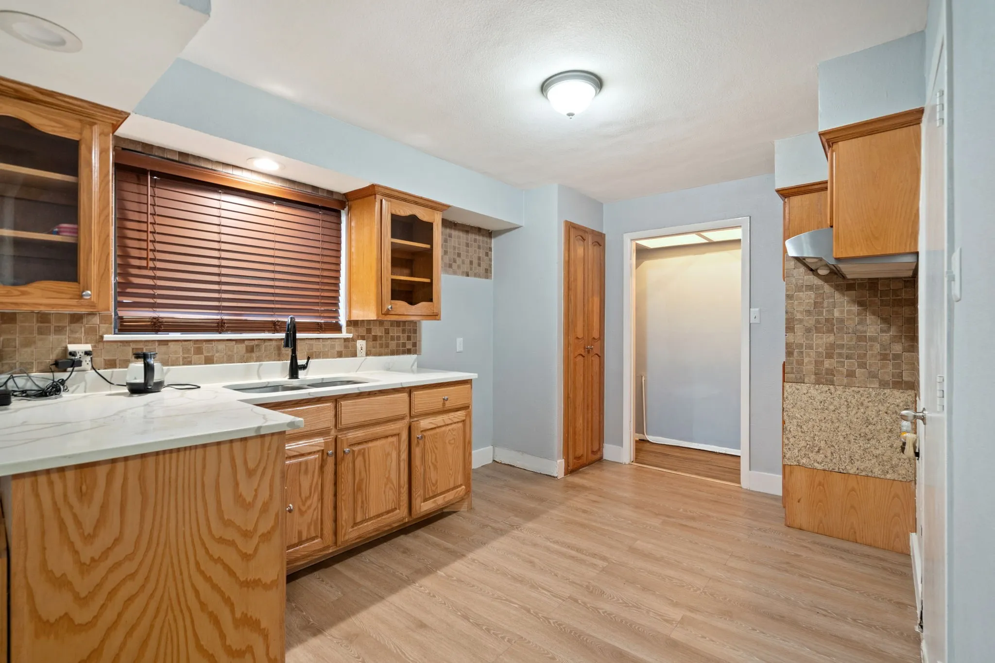 Kitchen featuring tasteful backsplash, glass fronted cabinets, and light wood finished floors