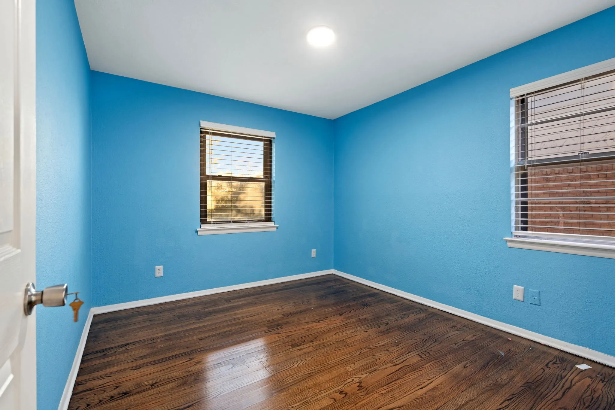 Spare room featuring dark wood-type flooring and a textured wall