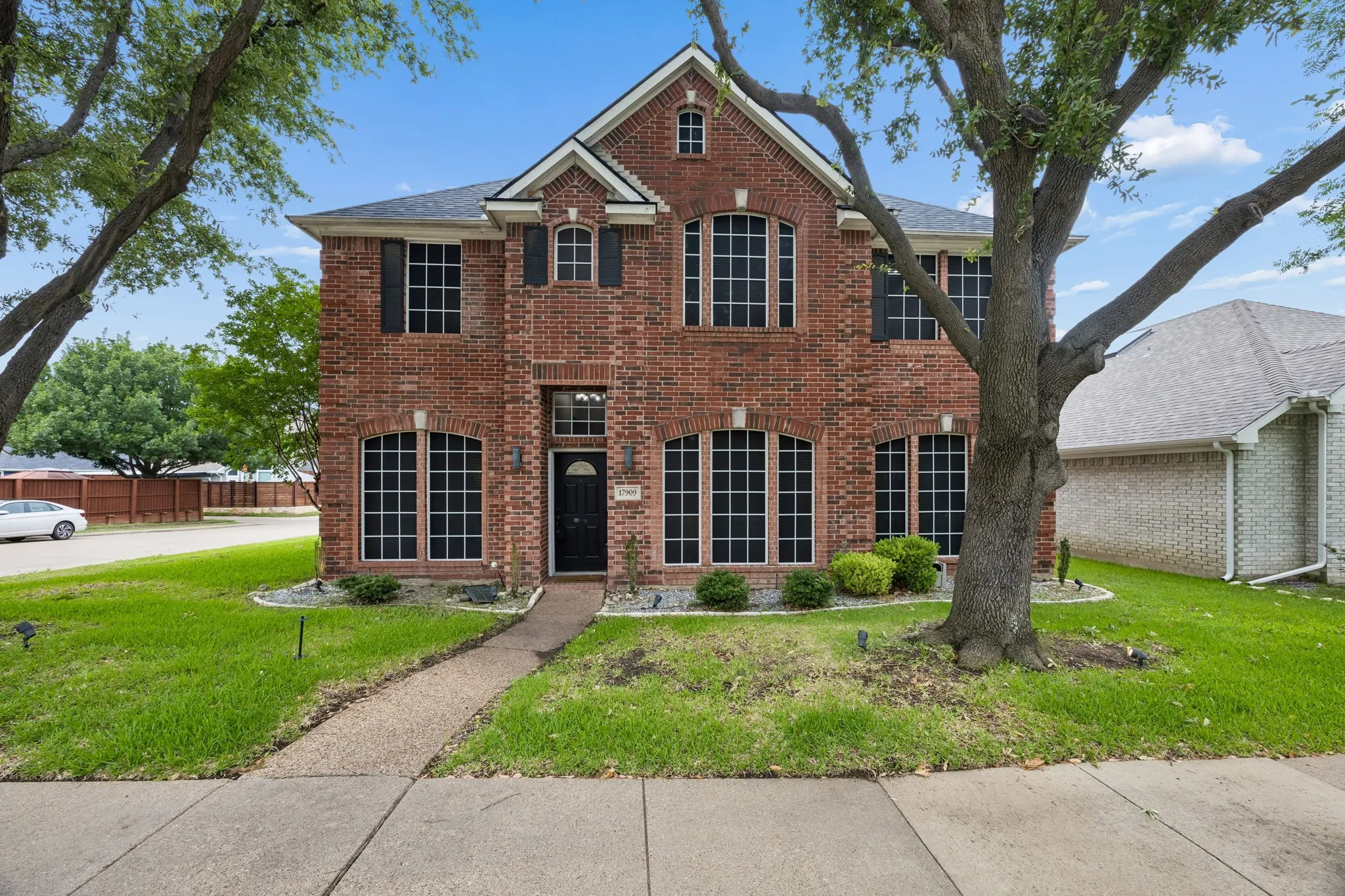 Two-story brick residence featuring a prominent front entrance, multiple arched windows with grids, and dark shutters