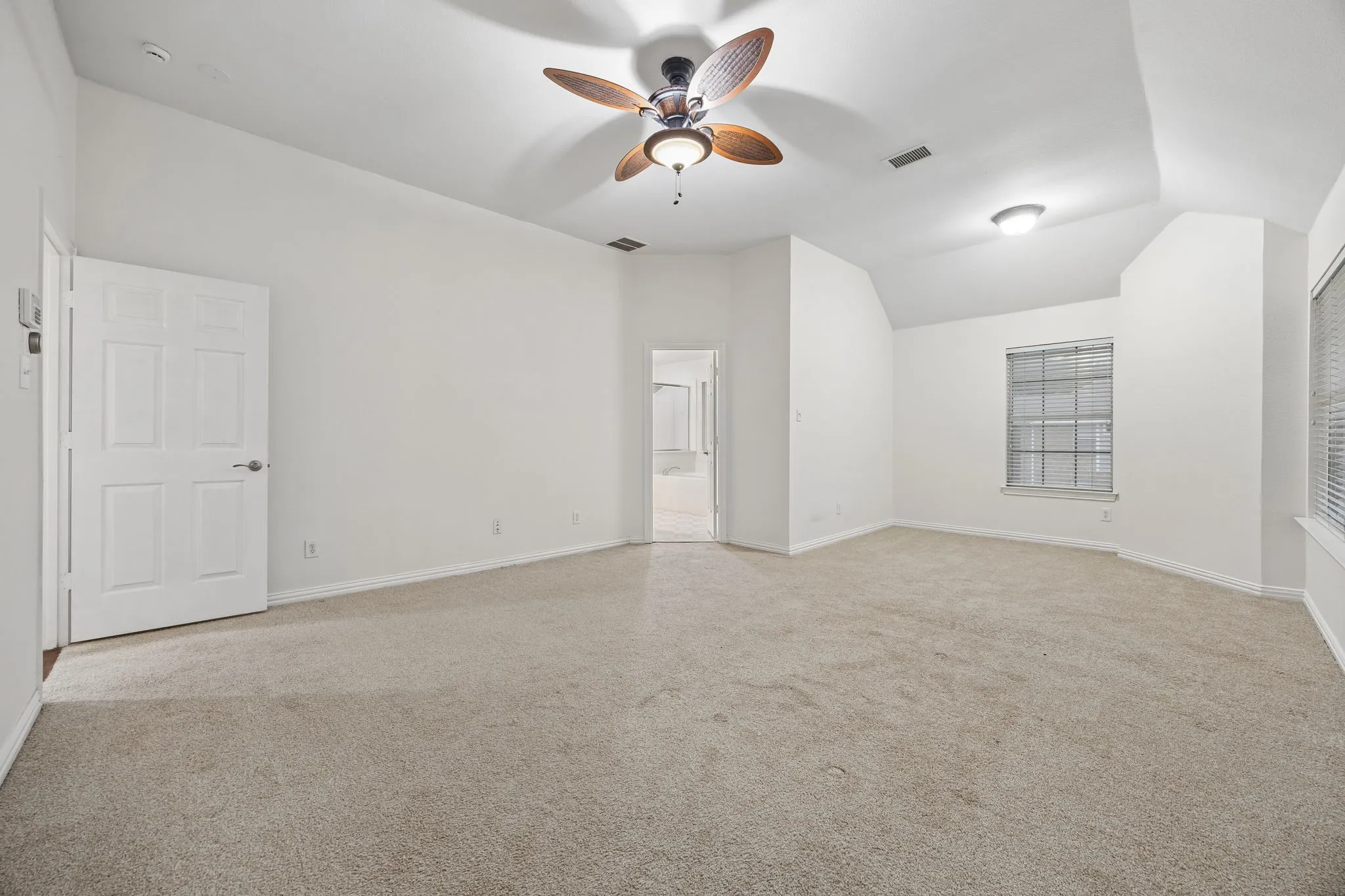 Carpeted room featuring a ceiling fan with integrated lighting, a tray ceiling, and a window with blinds