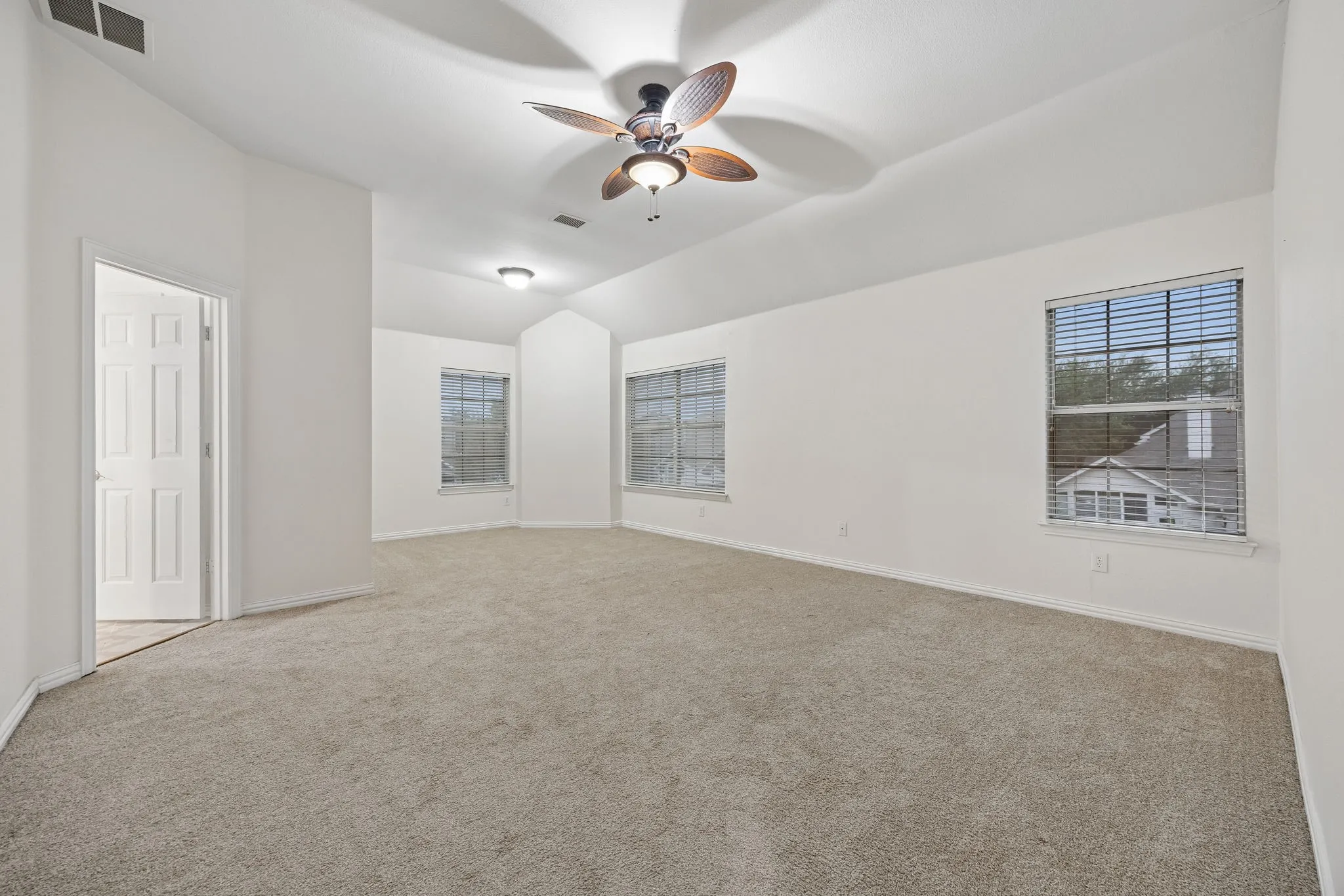 Spacious room featuring vaulted ceilings, a ceiling fan with integrated lighting, recessed lighting, and light-colored carpeting