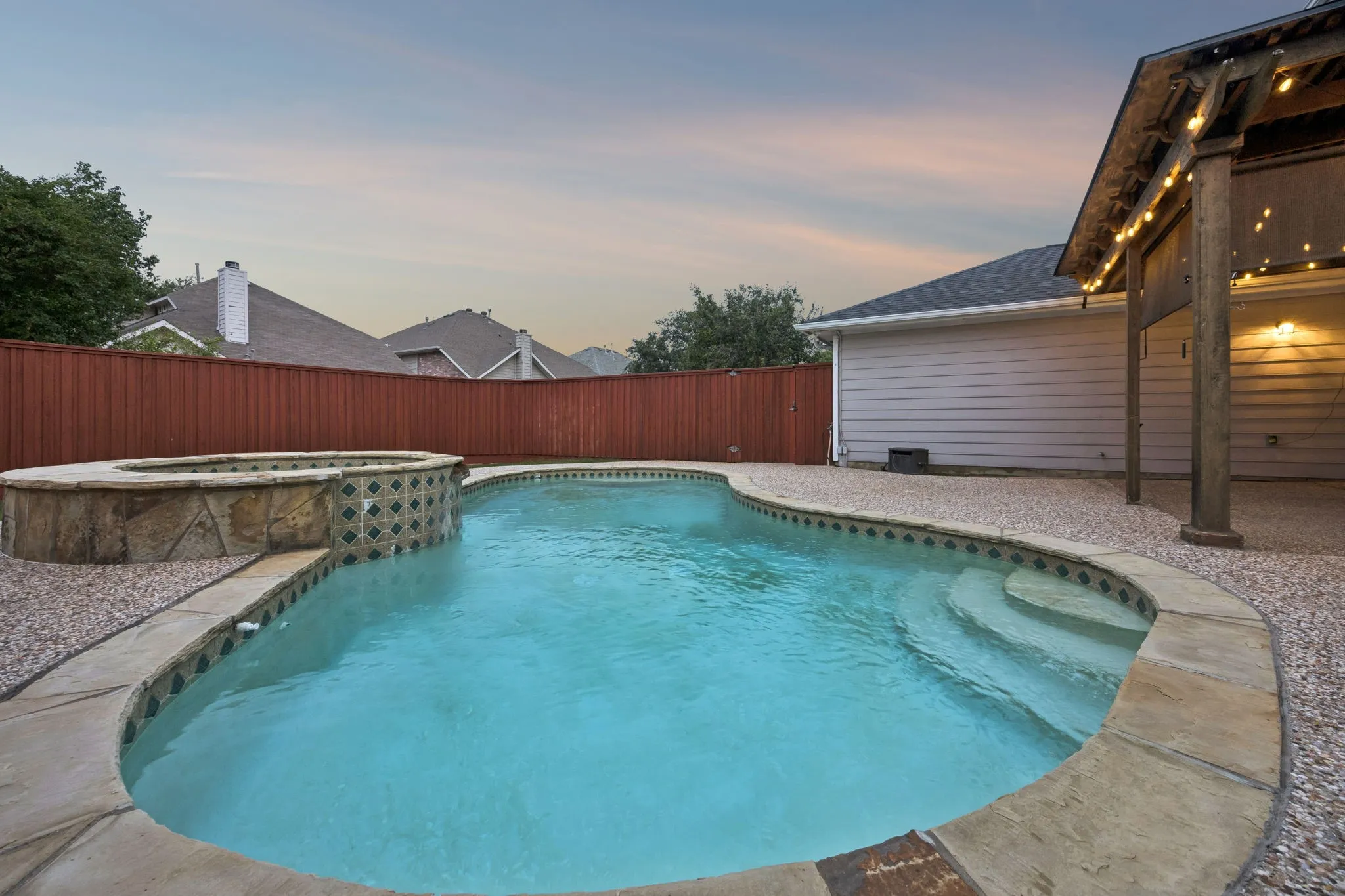 Kidney-shaped pool featuring stone coping and integrated spa with a stone and tile facade