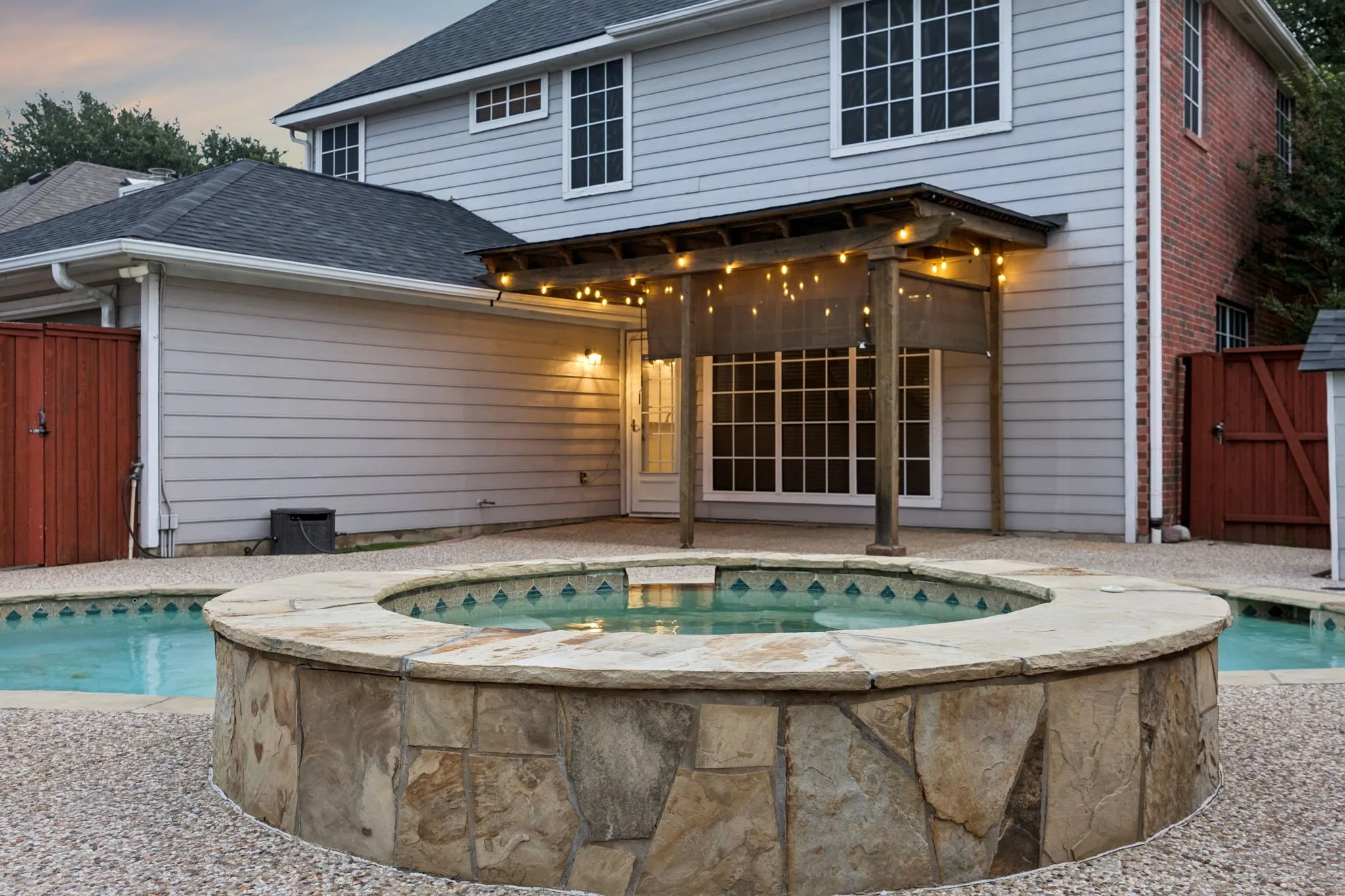Stone-clad spa with a flagstone coping, integrated into a pebble-finish pool deck