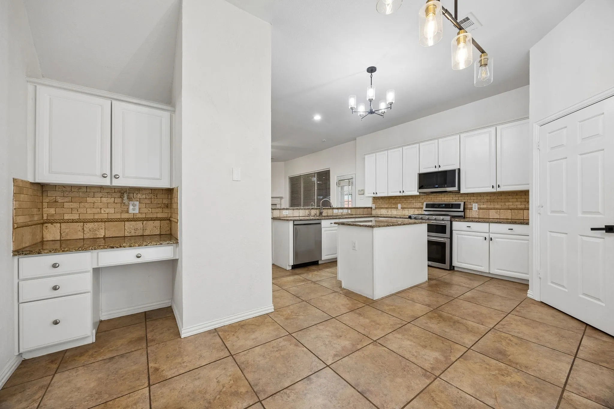 Open-concept kitchen featuring an island with a granite countertop, white cabinetry, stainless steel appliances, and tile flooring