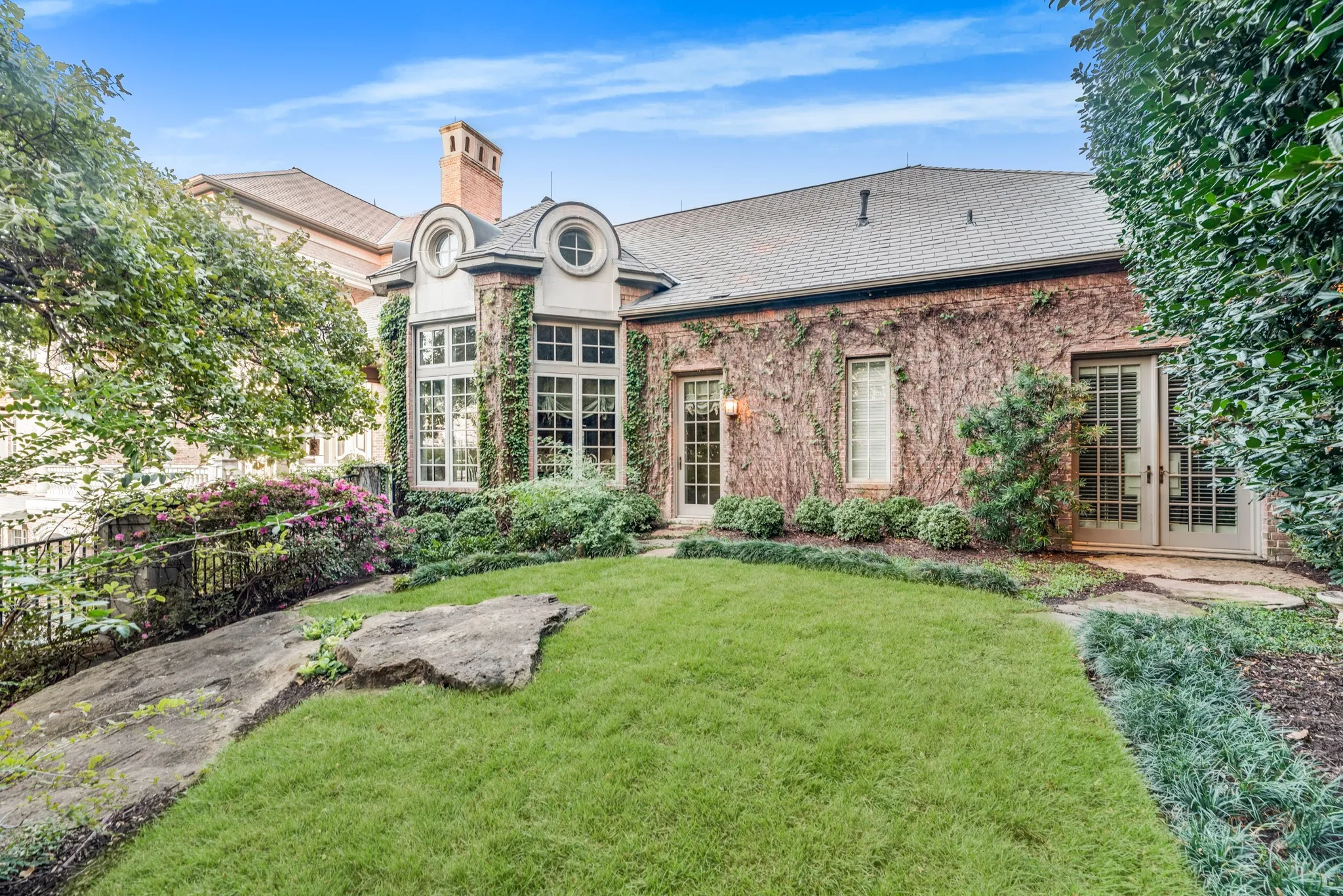 Grass area that leads to wooded acre with landscaped walking paths to the edge of the Trinity River