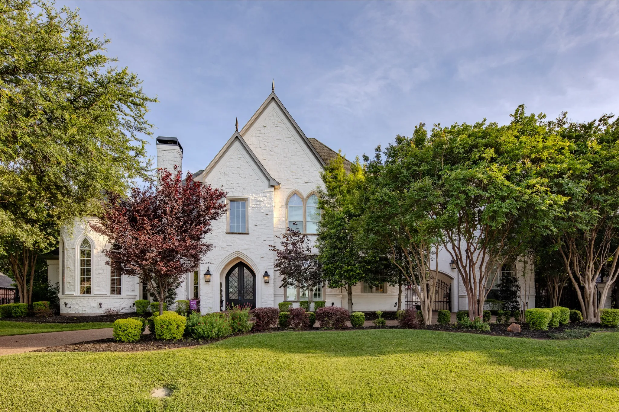 Distinguished white brick exterior featuring a prominent gabled roofline and arched entry
