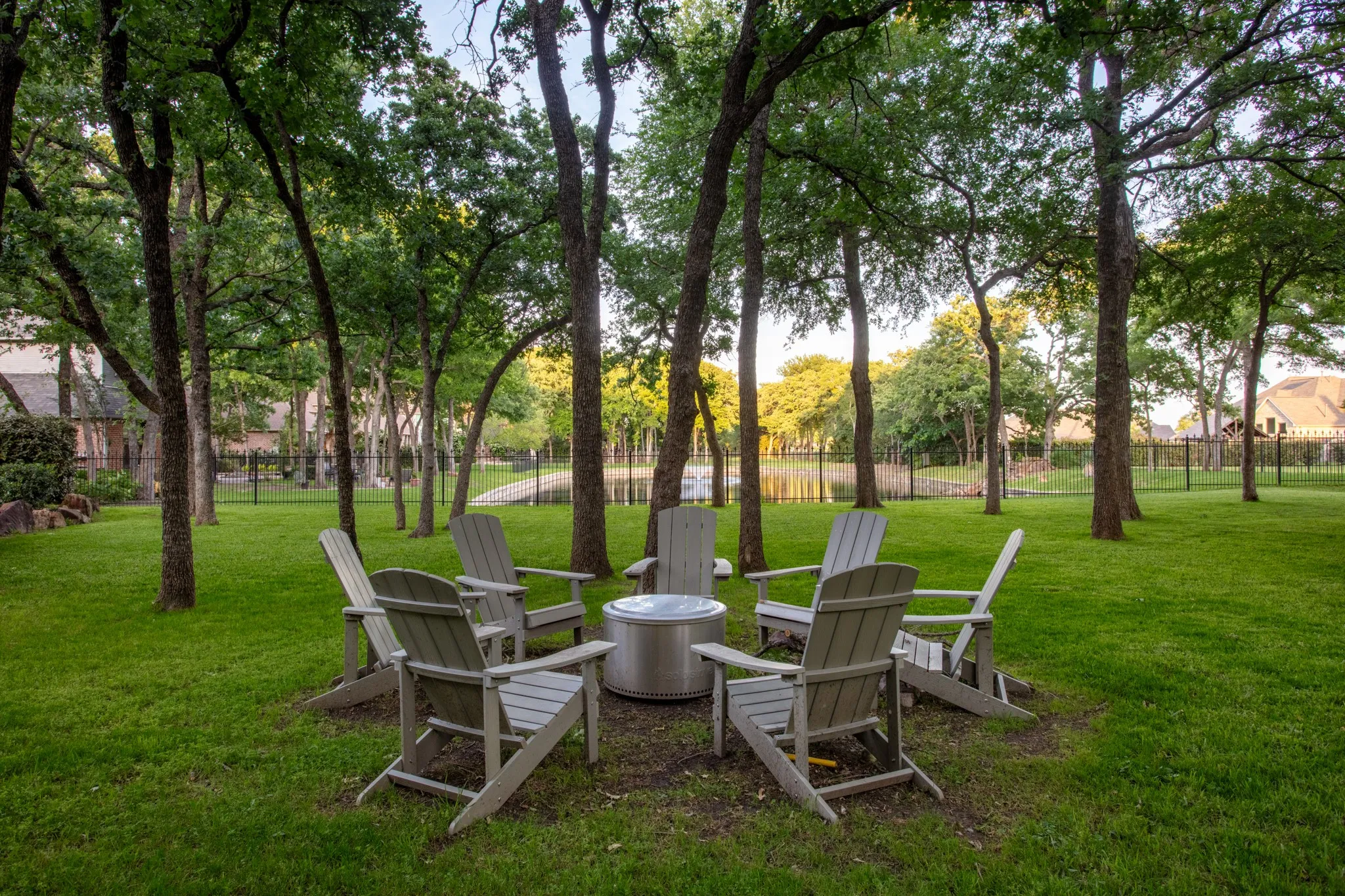 Expansive lawn area featuring mature trees and a tranquil water feature