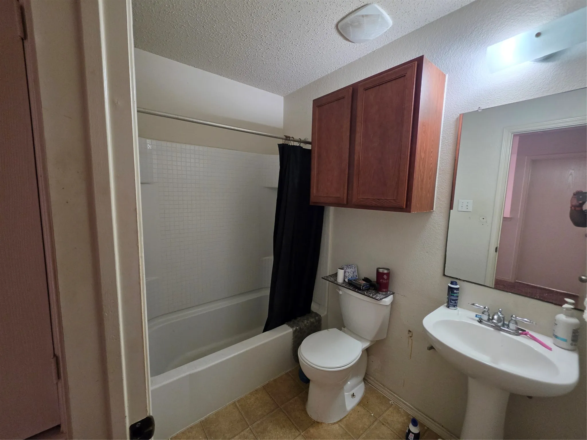 Full bathroom featuring a textured ceiling, shower / bath combo, and light tile patterned floors