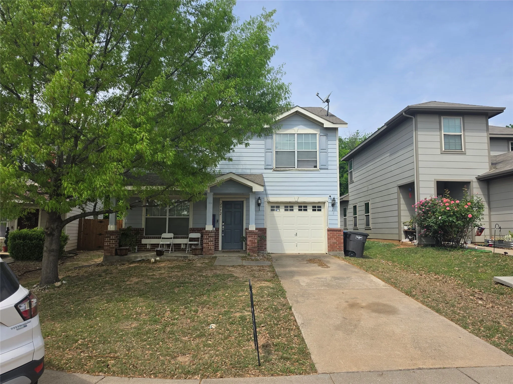 View of front of home featuring brick siding, driveway, a garage, and a front lawn
