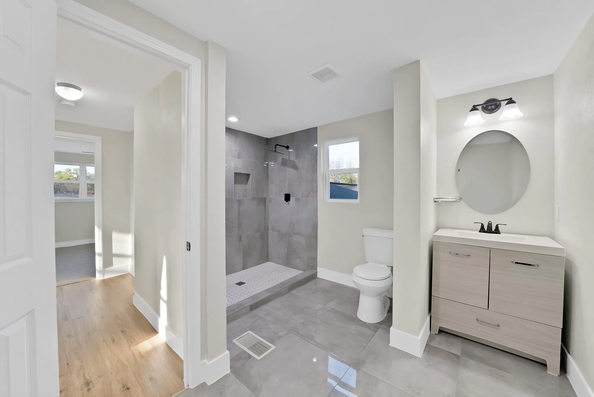 Bathroom with tiled shower, vanity, and light tile patterned floors