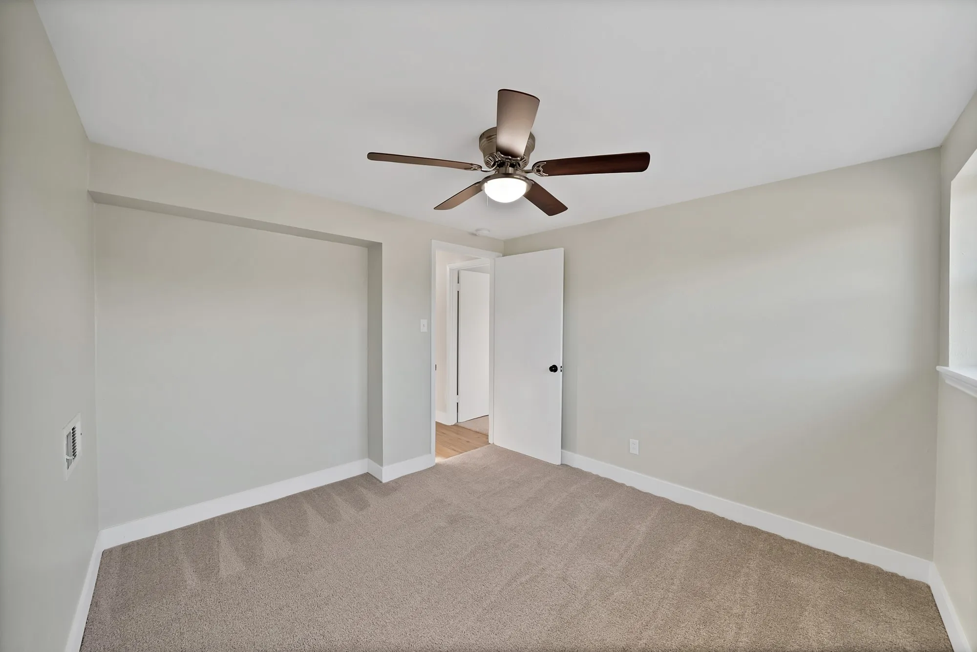 Unfurnished bedroom with light colored carpet and ceiling fan