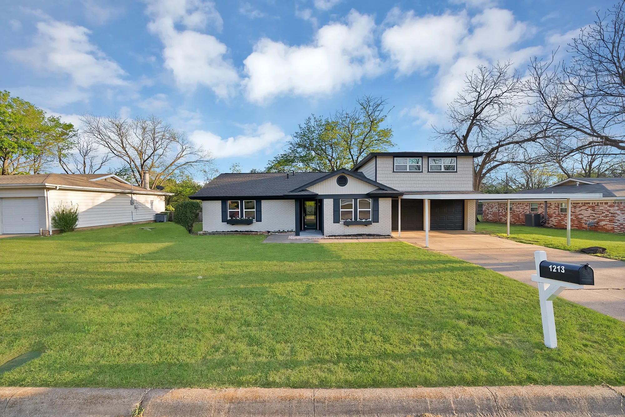 Traditional-style house with a front lawn, a garage, concrete driveway, and brick siding