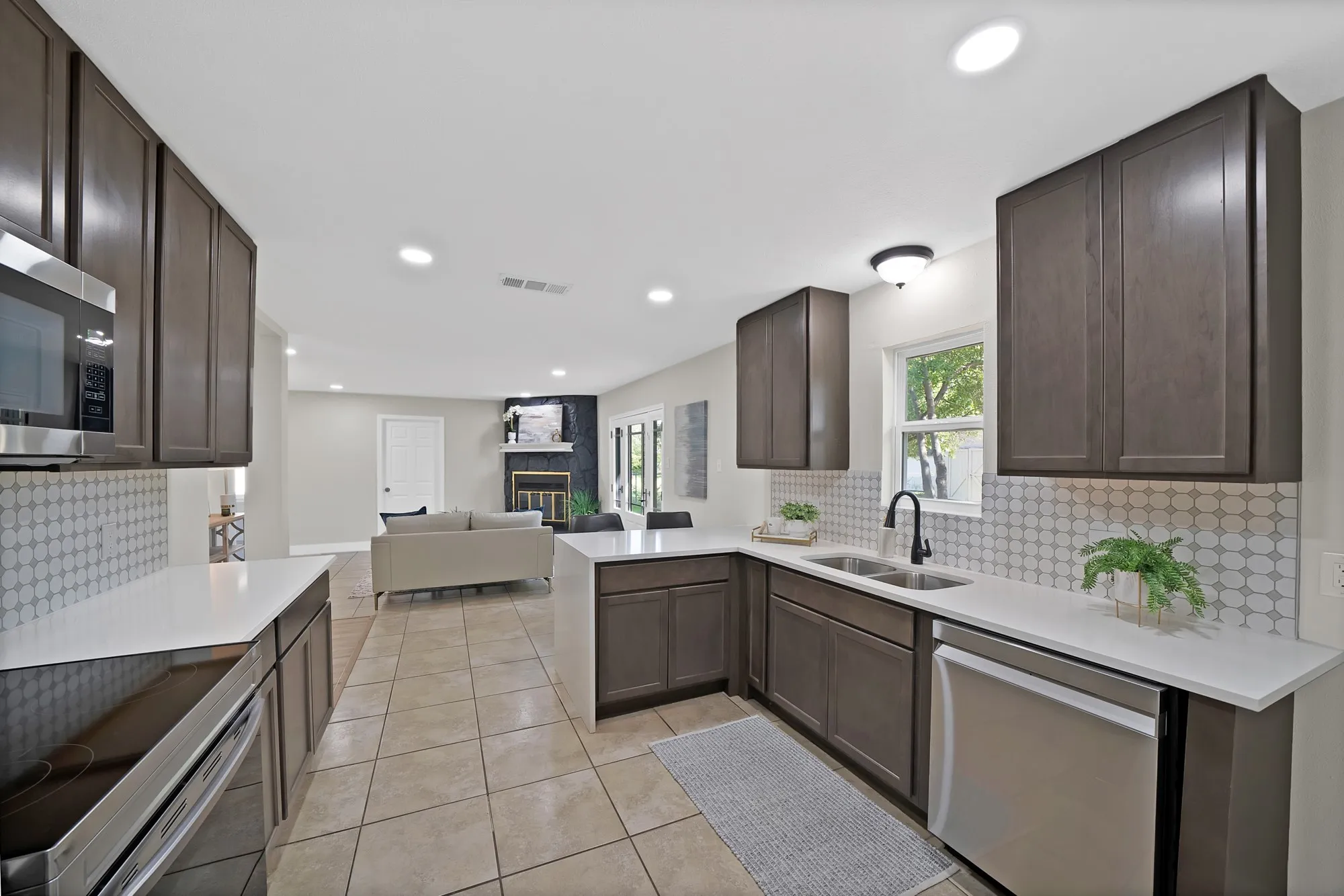 Kitchen featuring dark wood finish cabinetry, open floor plan, a large fireplace, stainless steel appliances, and recessed lighting