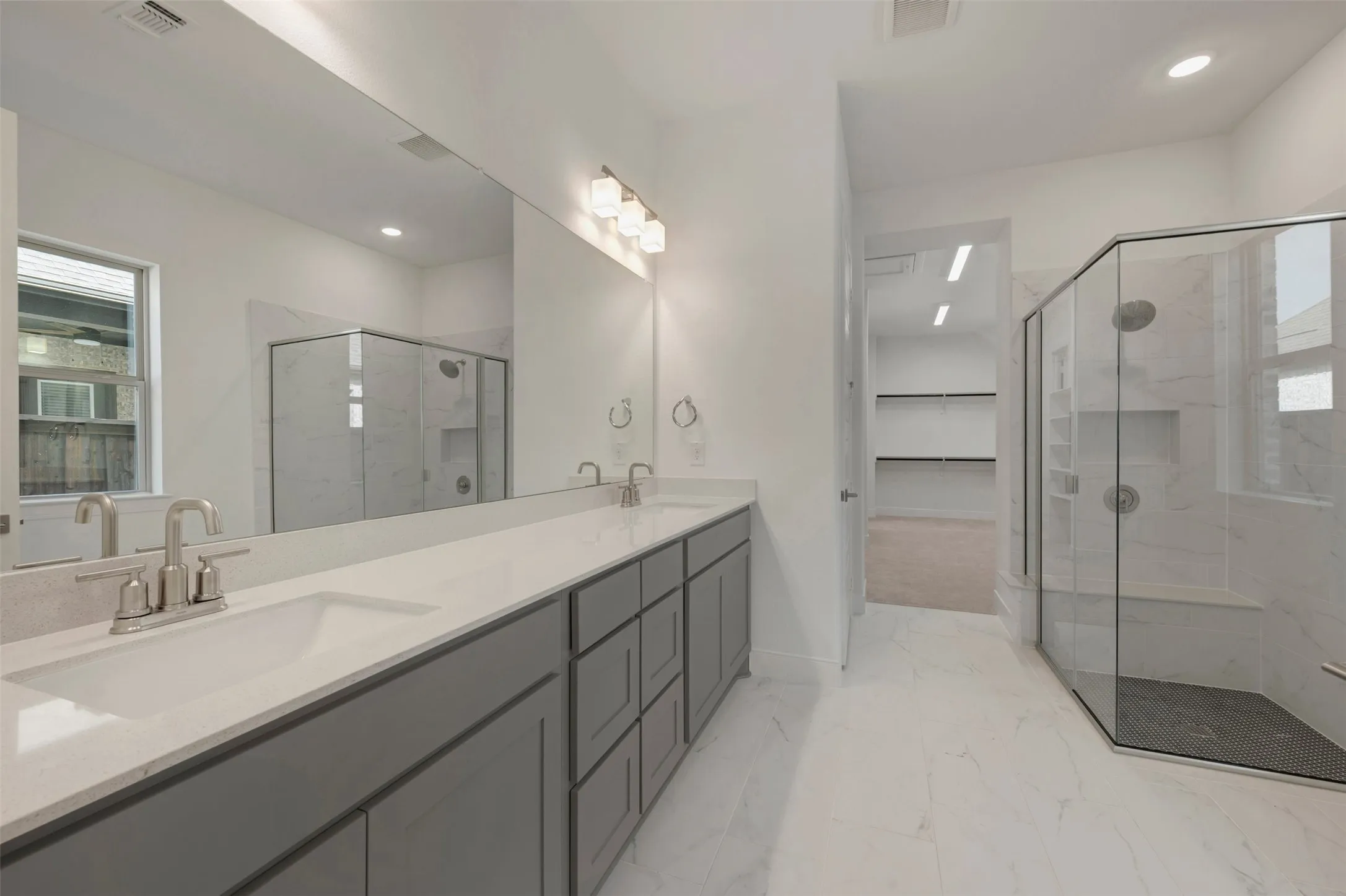 Bathroom with double vanity featuring gray cabinetry and light-toned countertops