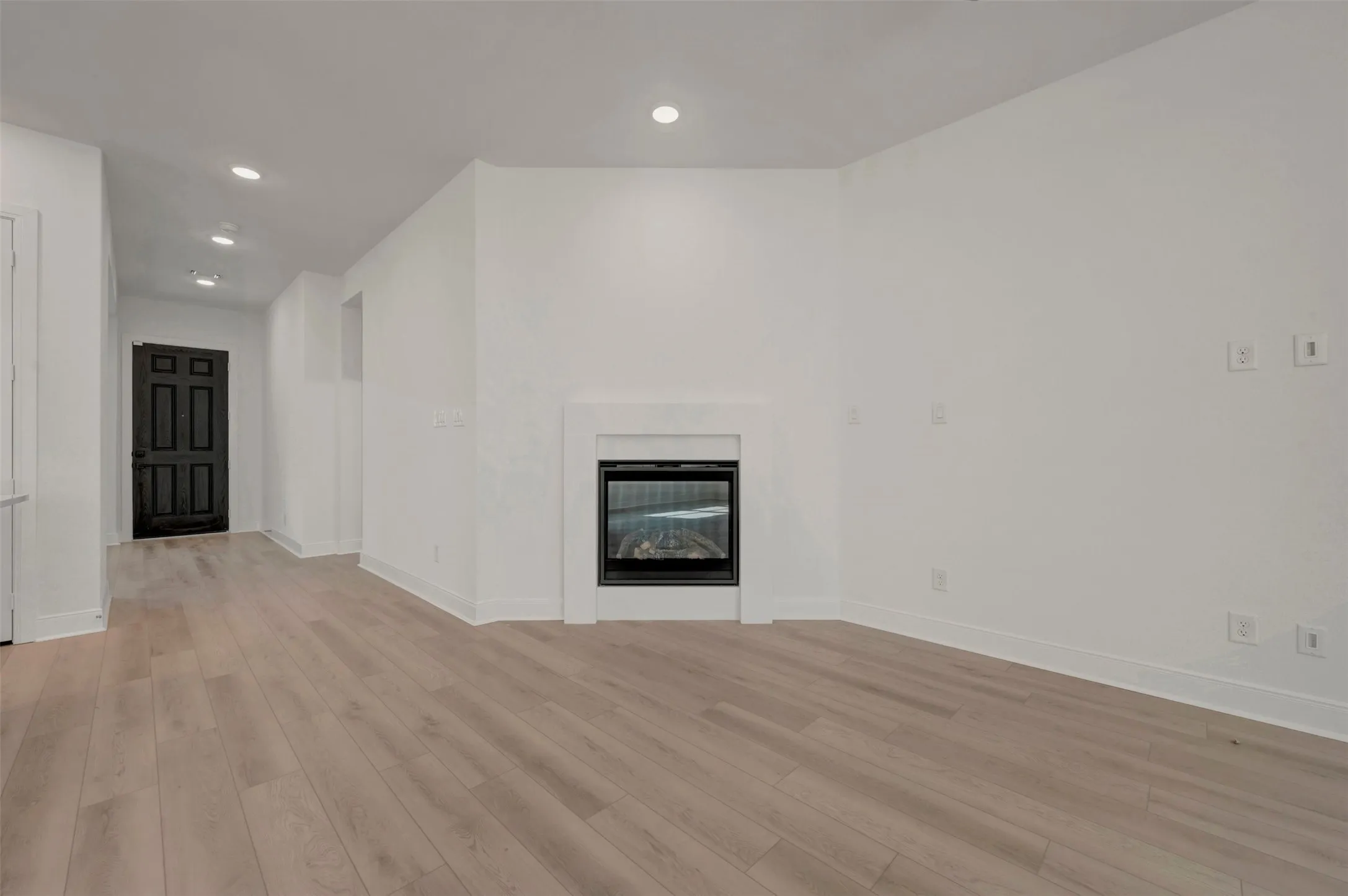 Living area featuring a built-in fireplace with a white surround, recessed lighting, and light wood-finish flooring