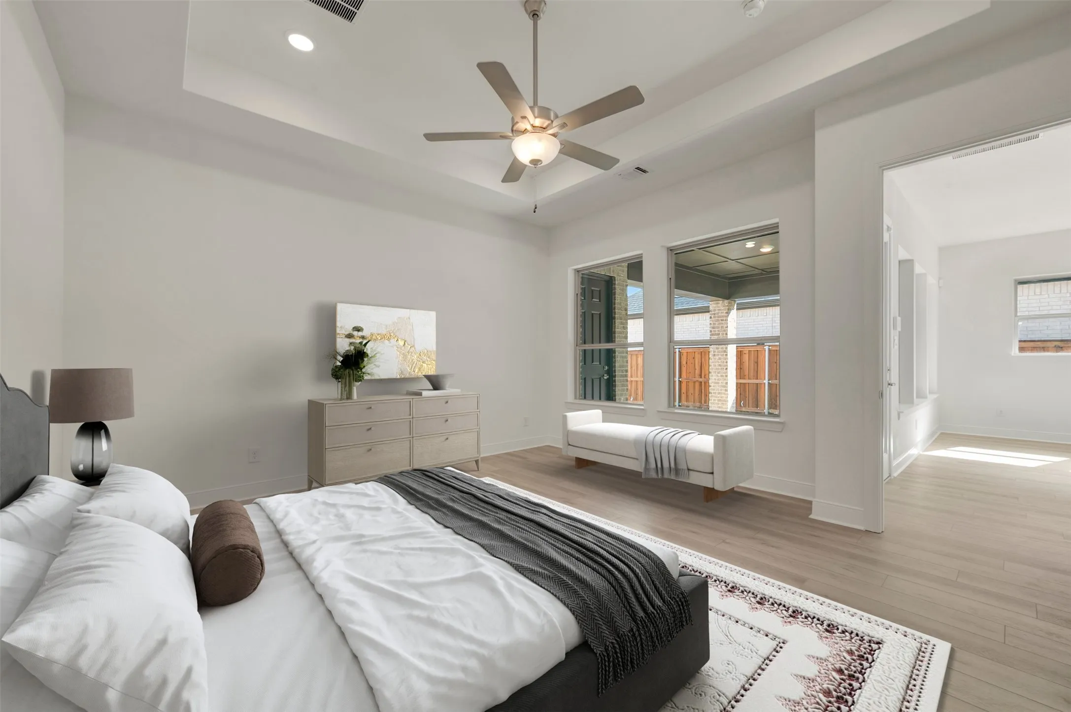 Spacious bedroom featuring a tray ceiling, recessed lighting, and a ceiling fan