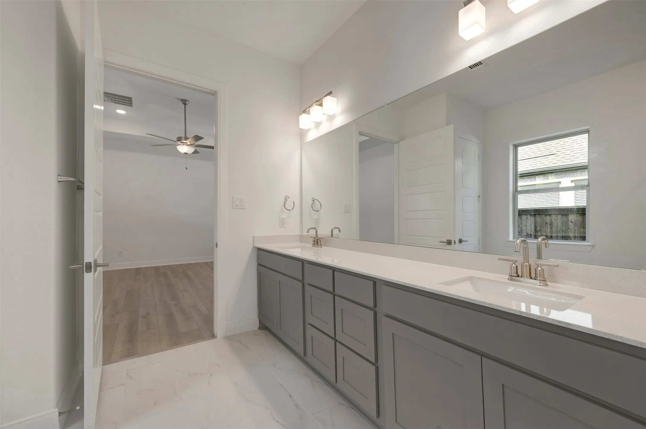 Bathroom vanity featuring dual sinks, gray cabinetry, and a light-colored countertop