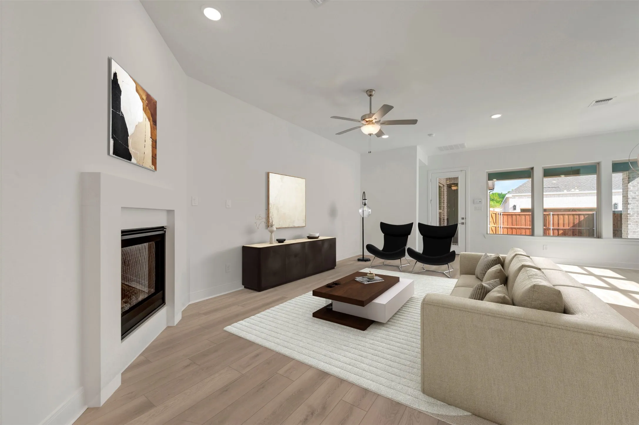 Living area featuring light wood-finish flooring, a contemporary fireplace, vaulted ceilings with recessed lighting, a ceiling fan, and multiple windows