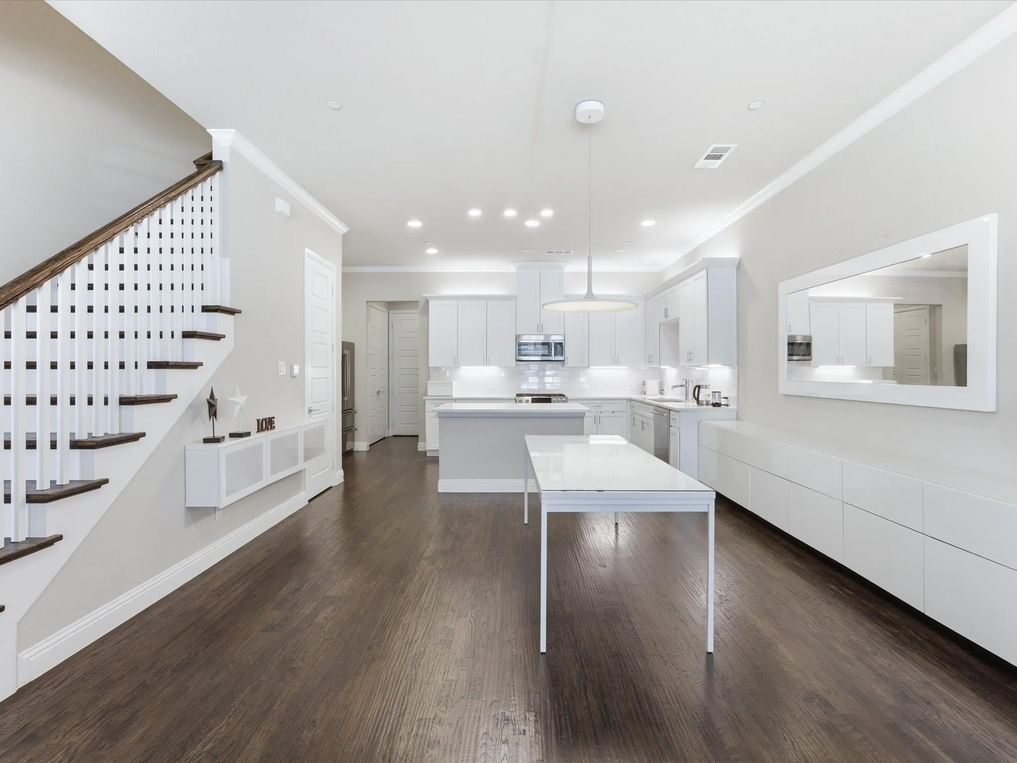Kitchen featuring white cabinets, a kitchen island, stainless steel appliances, crown molding, and dark wood-type flooring