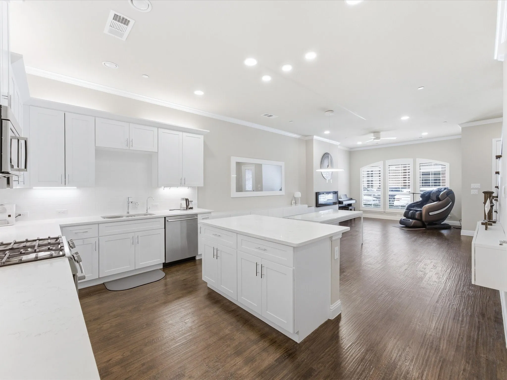 Kitchen featuring white cabinets, crown molding, open floor plan, dark wood-type flooring, and stainless steel appliances
