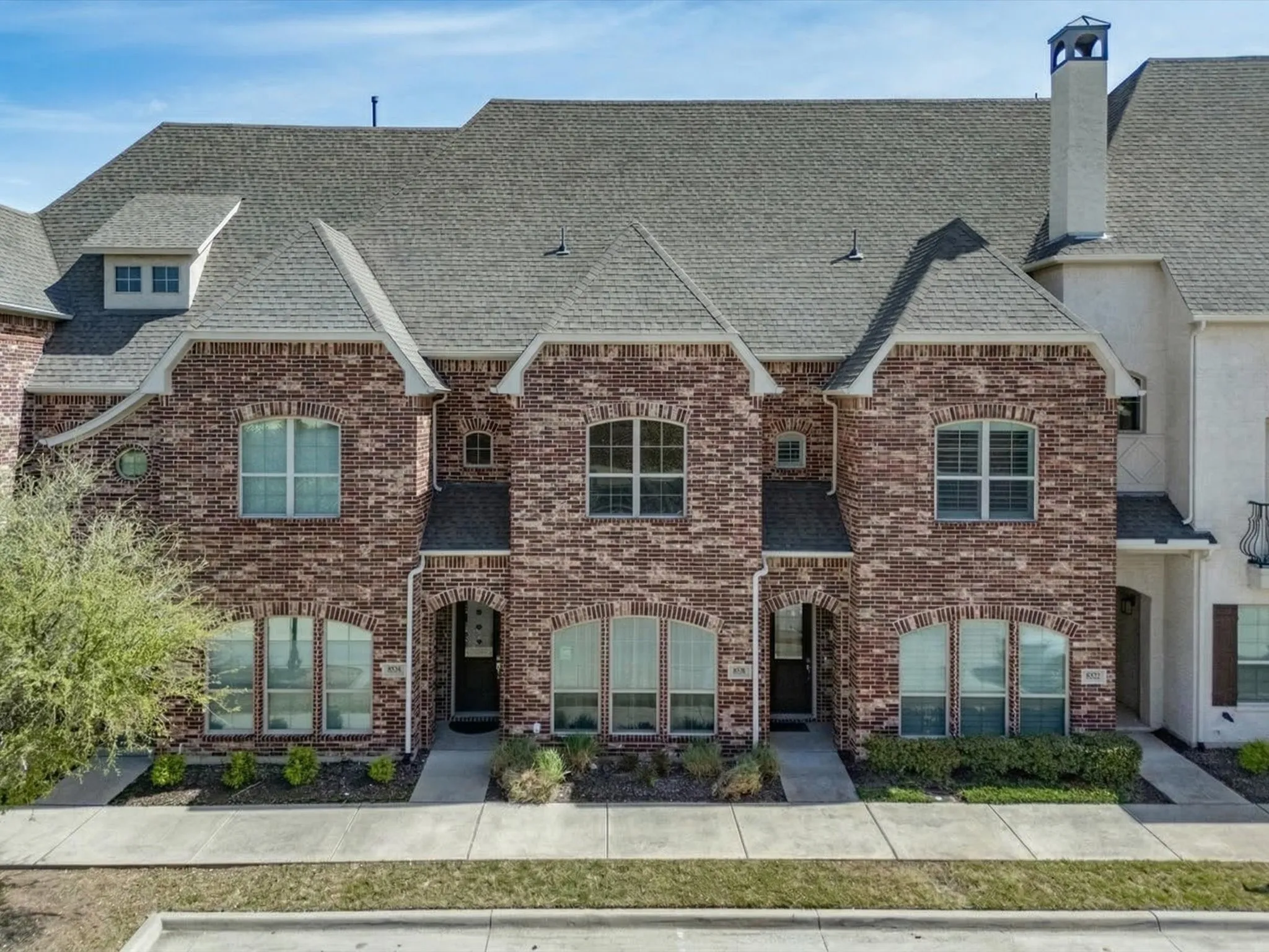 View of front facade featuring roof with shingles, brick siding, and a chimney