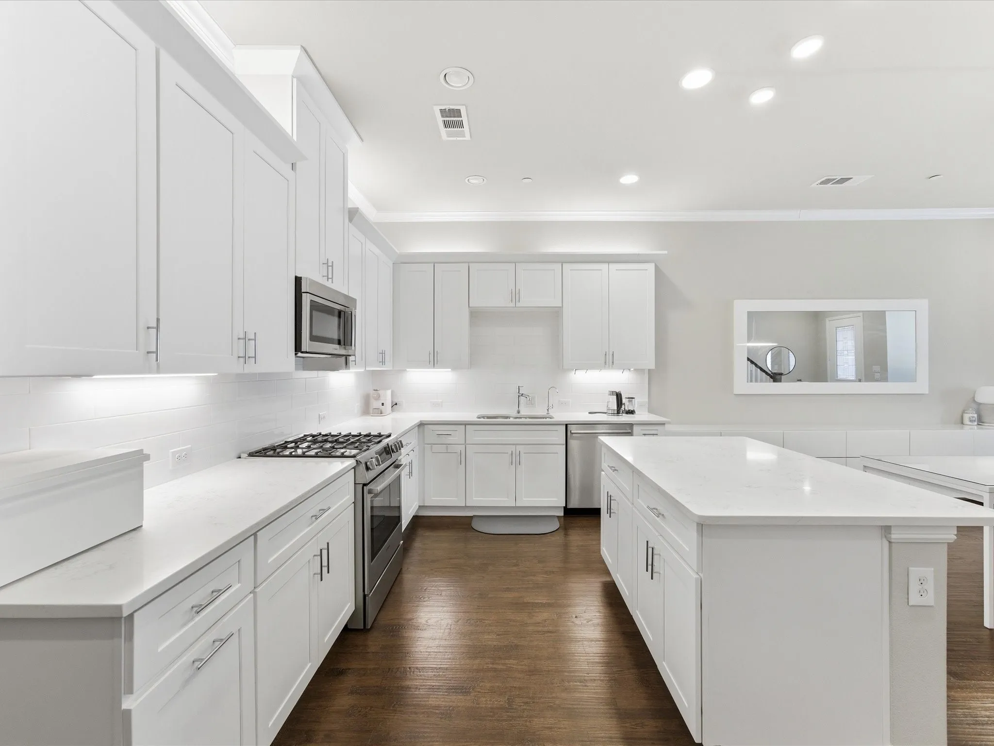 Kitchen featuring stainless steel appliances, a kitchen island, crown molding, white cabinets, and recessed lighting