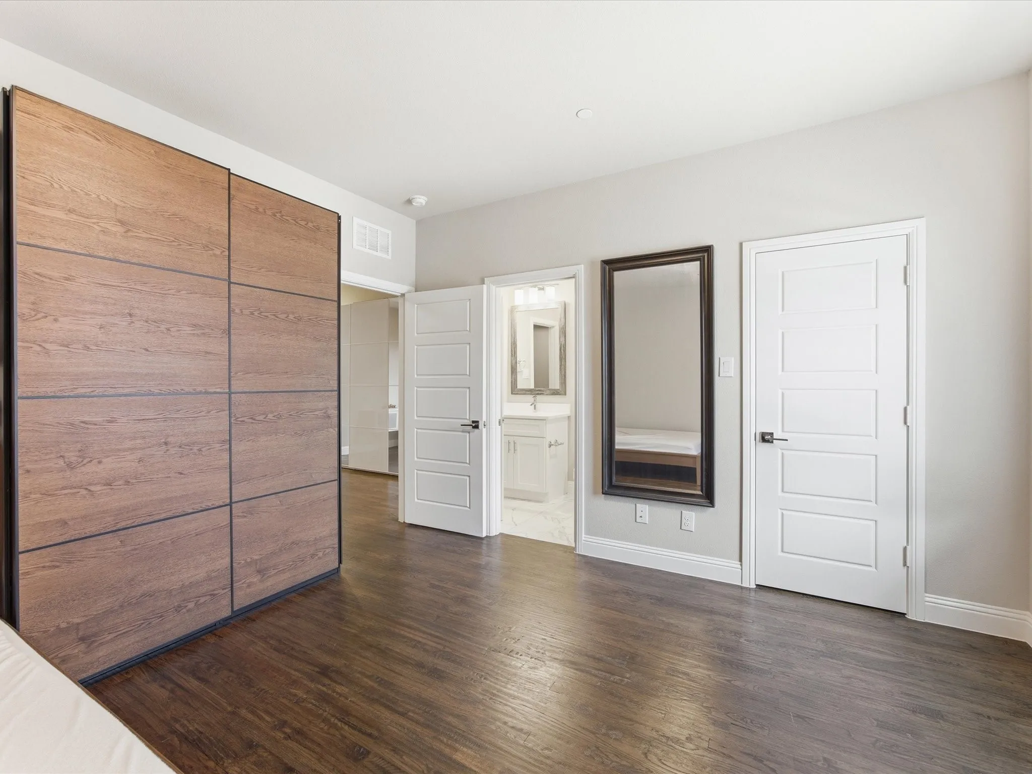 Unfurnished bedroom with dark wood-type flooring, connected bathroom, and a closet