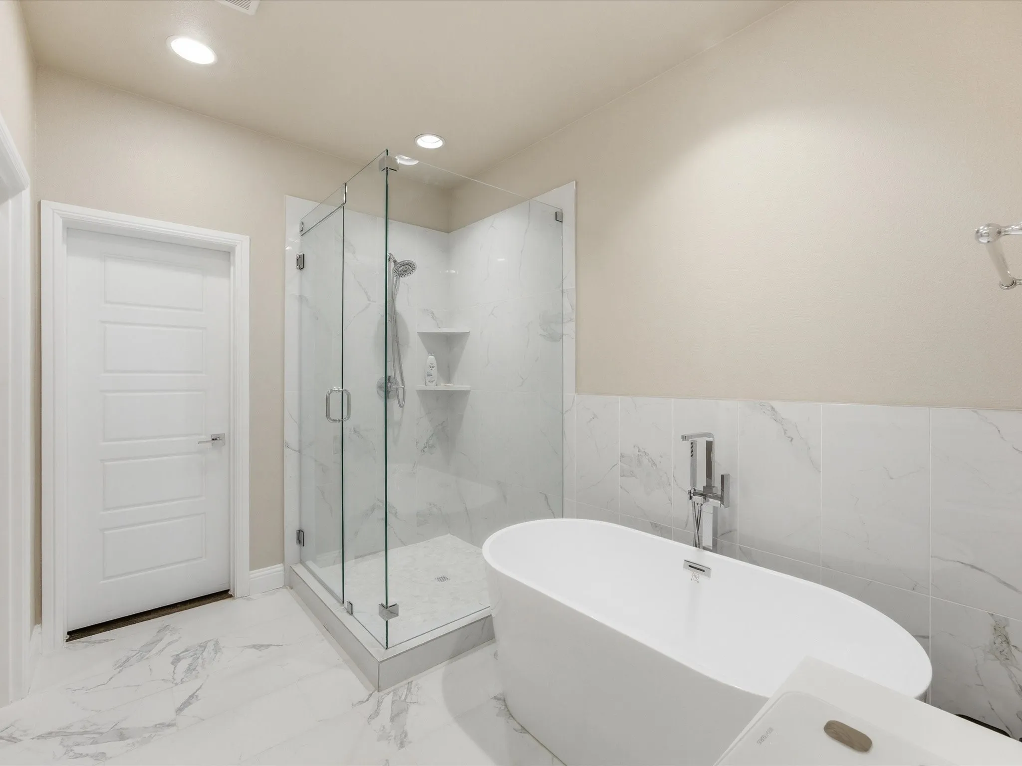 Primary bathroom with a marble finish shower, a soaking tub, light marble finish floors, recessed lighting, and tile walls