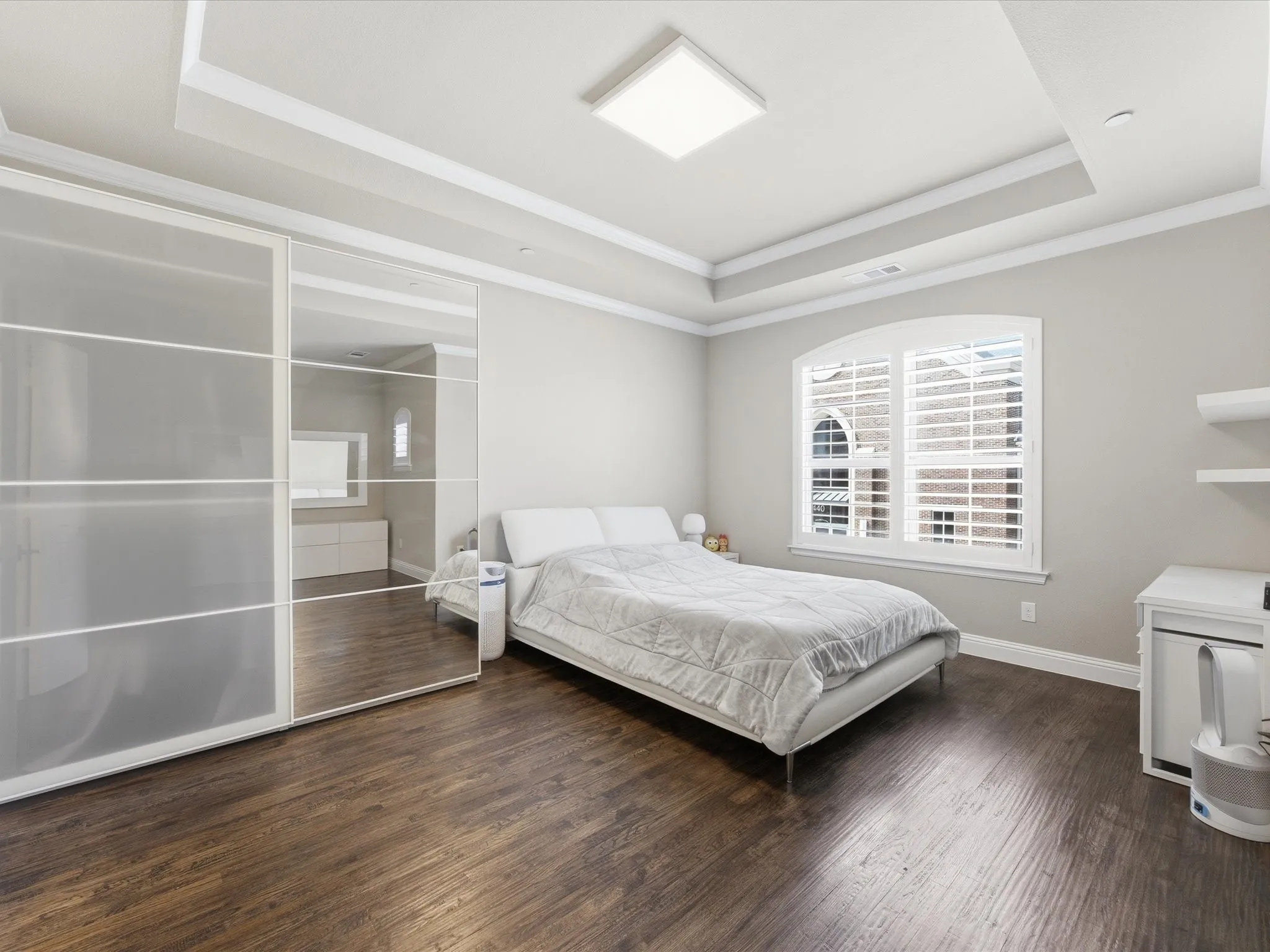 Primary Bedroom with dark wood-type flooring, a tray ceiling, and ornamental molding