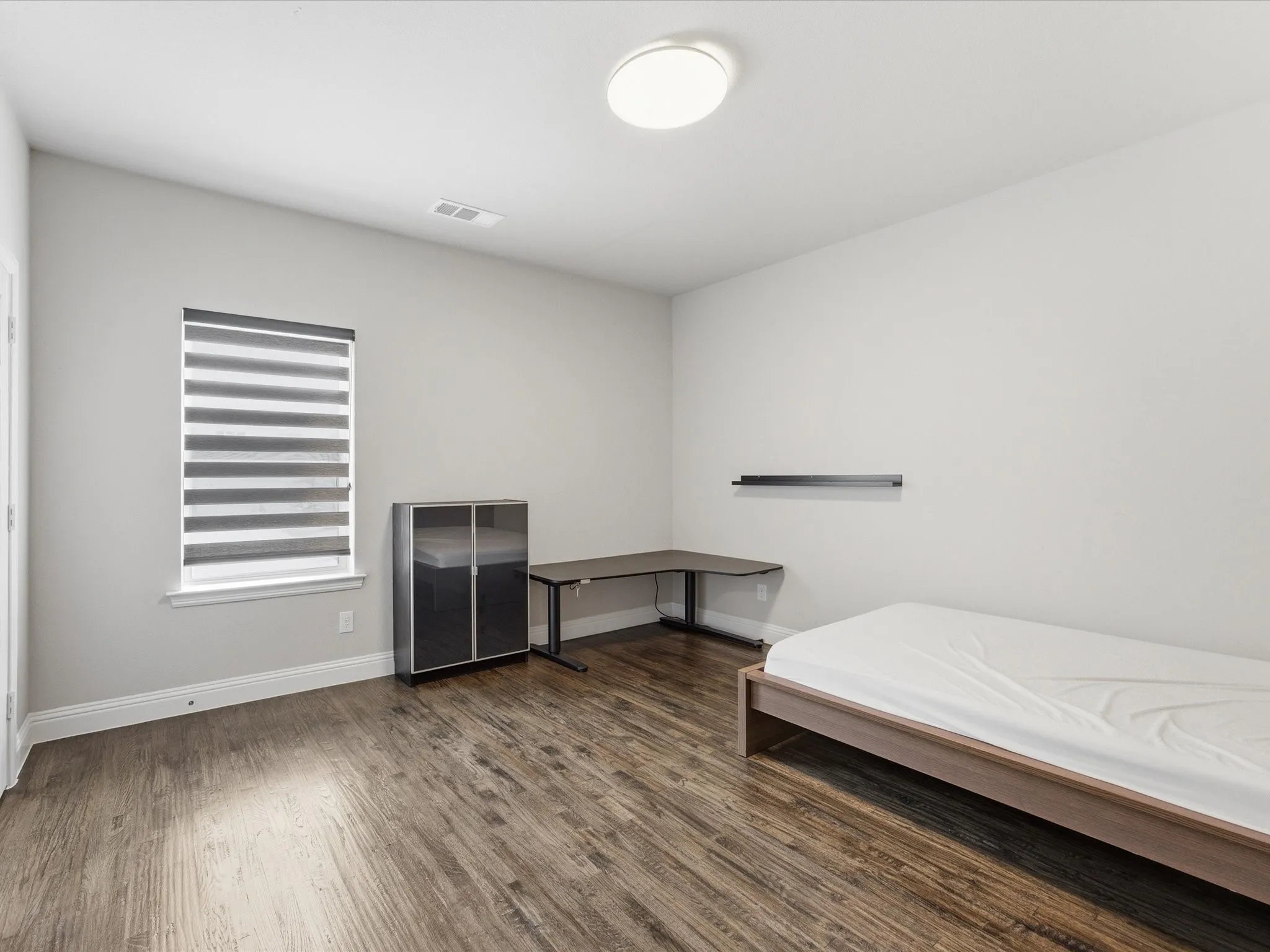 Bedroom with dark wood finished floors and baseboards