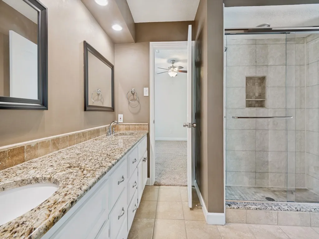 Bathroom with double vanity, a stall shower, light tile patterned floors, recessed lighting, and a ceiling fan