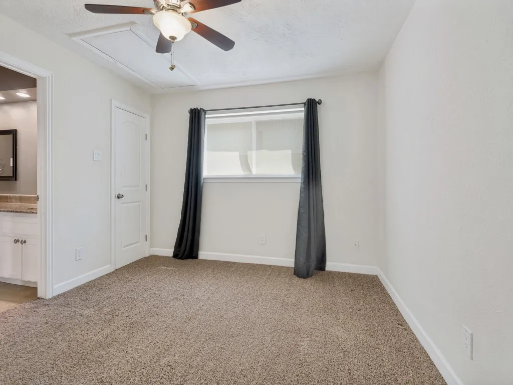 Secondary Bedroom with light carpet, ensuite bath, a ceiling fan, and a textured ceiling