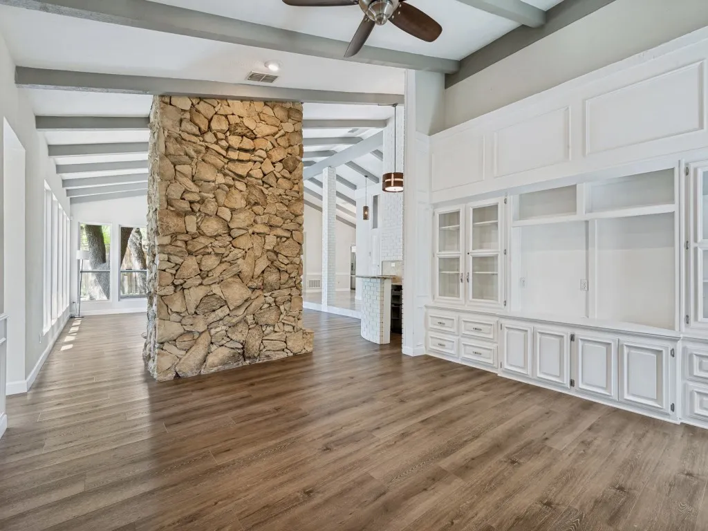 Living room with ceiling fan, dark wood-style floors, and vaulted ceiling with beams