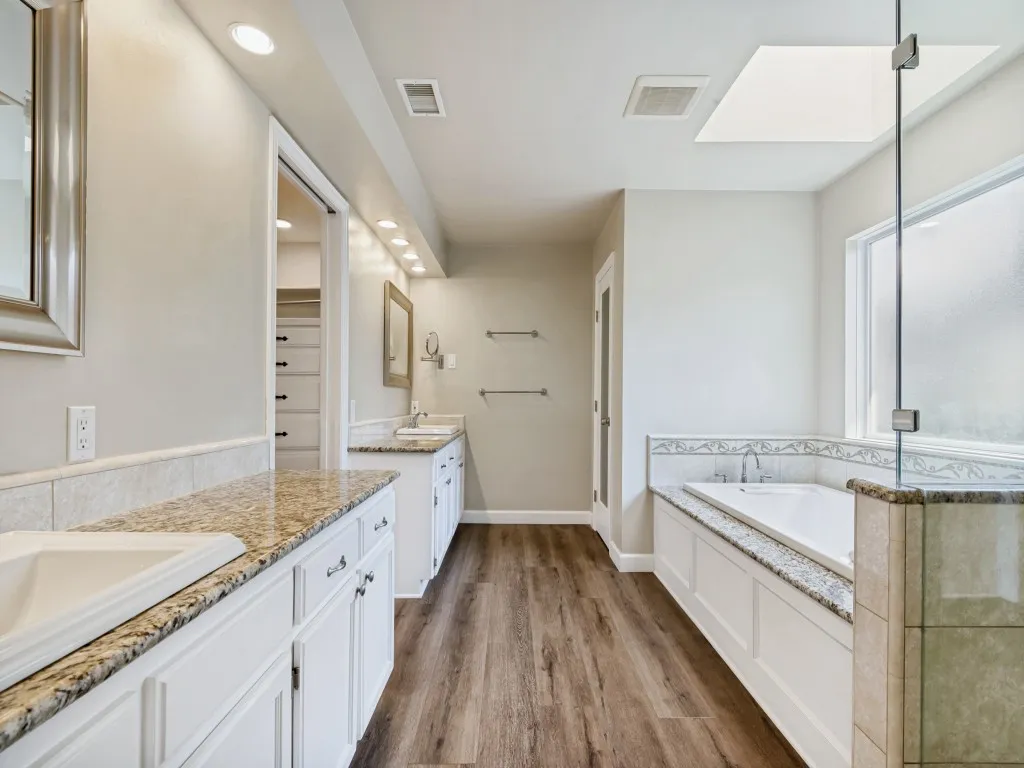 Primary Bathroom with vanity, a shower stall, a bath, and dark wood-type flooring