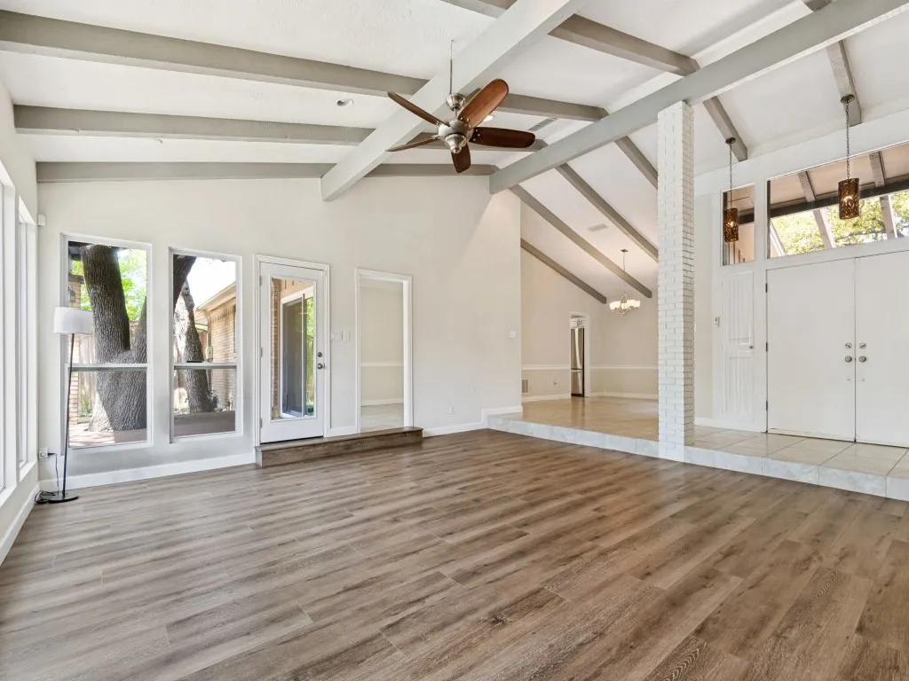 Living room with great view of the backyard, healthy amount of natural light, a ceiling fan, and dark wood-style floors