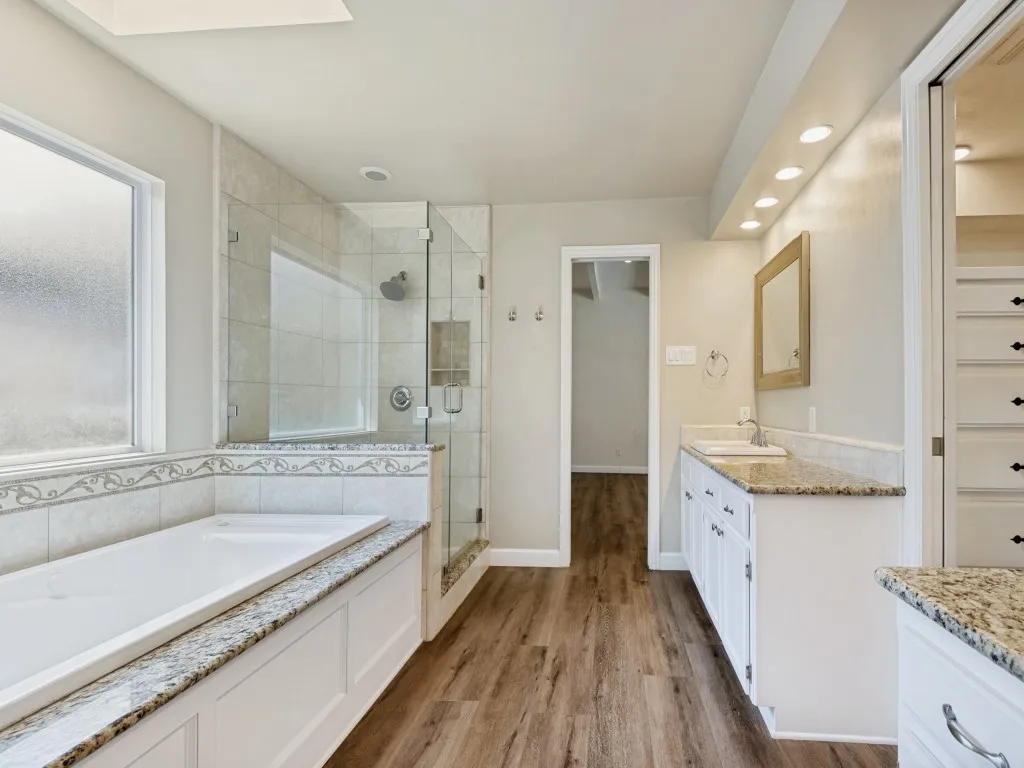 Bathroom featuring vanity, a stall shower, a bath, dark wood finished floors, and recessed lighting