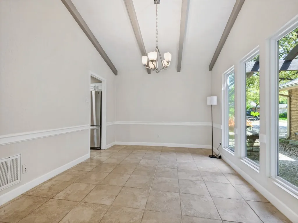 Dining area with a chandelier, vaulted ceiling with beams, and light tile patterned floors