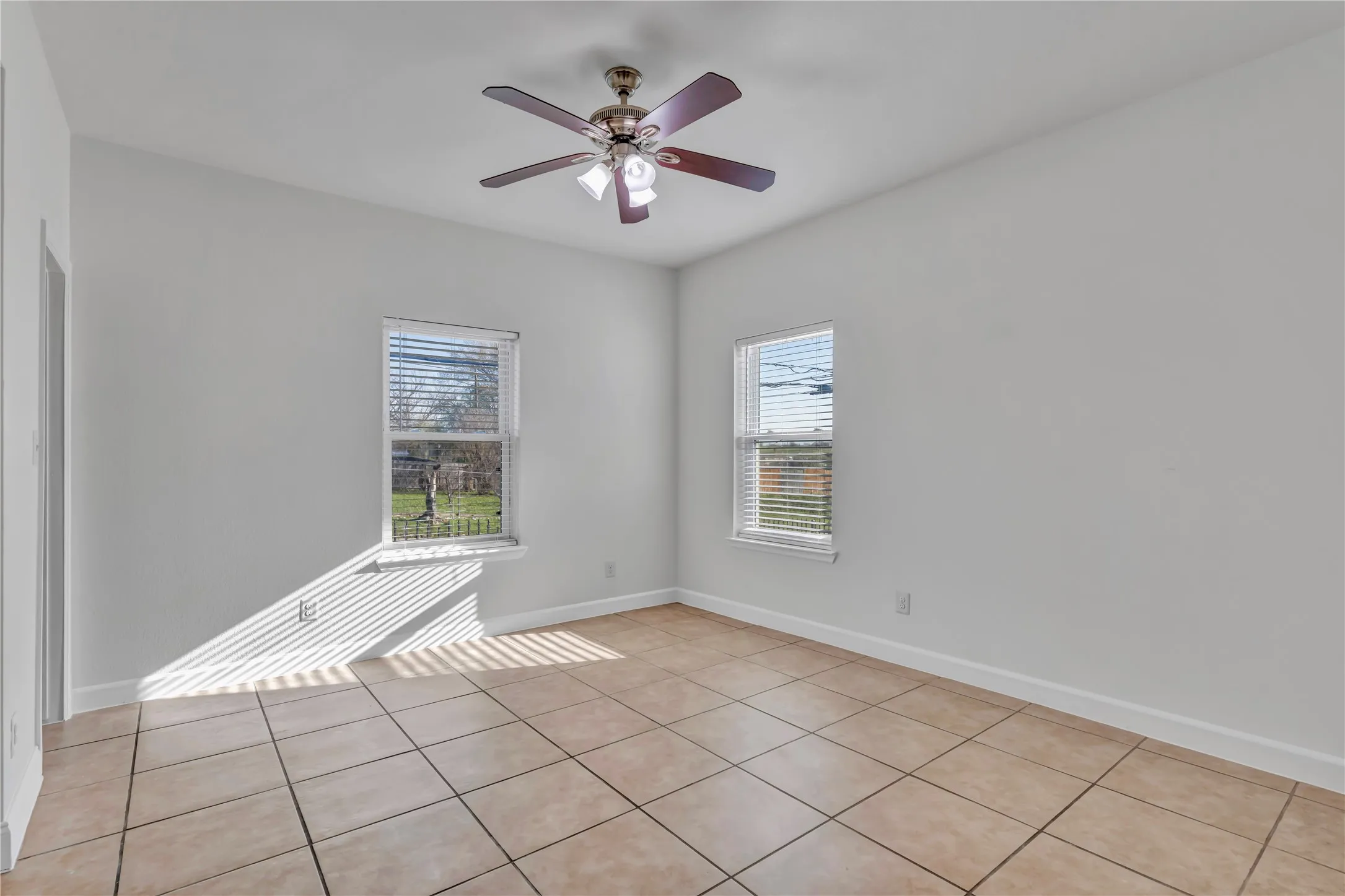 Empty room with ceiling fan and light tile patterned floors