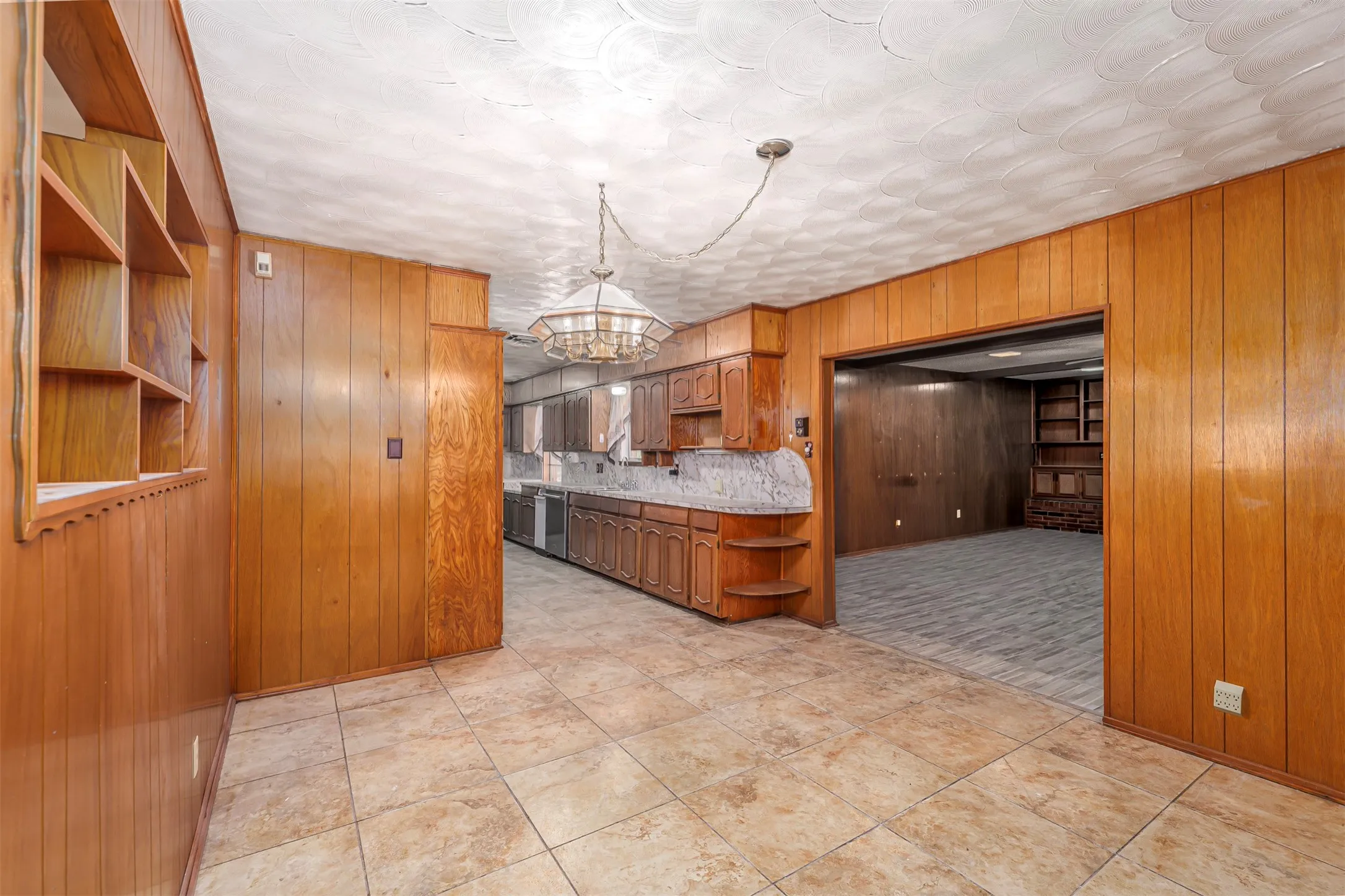 Kitchen with wooden walls, open shelves, wood finish cabinetry, light countertops, and backsplash