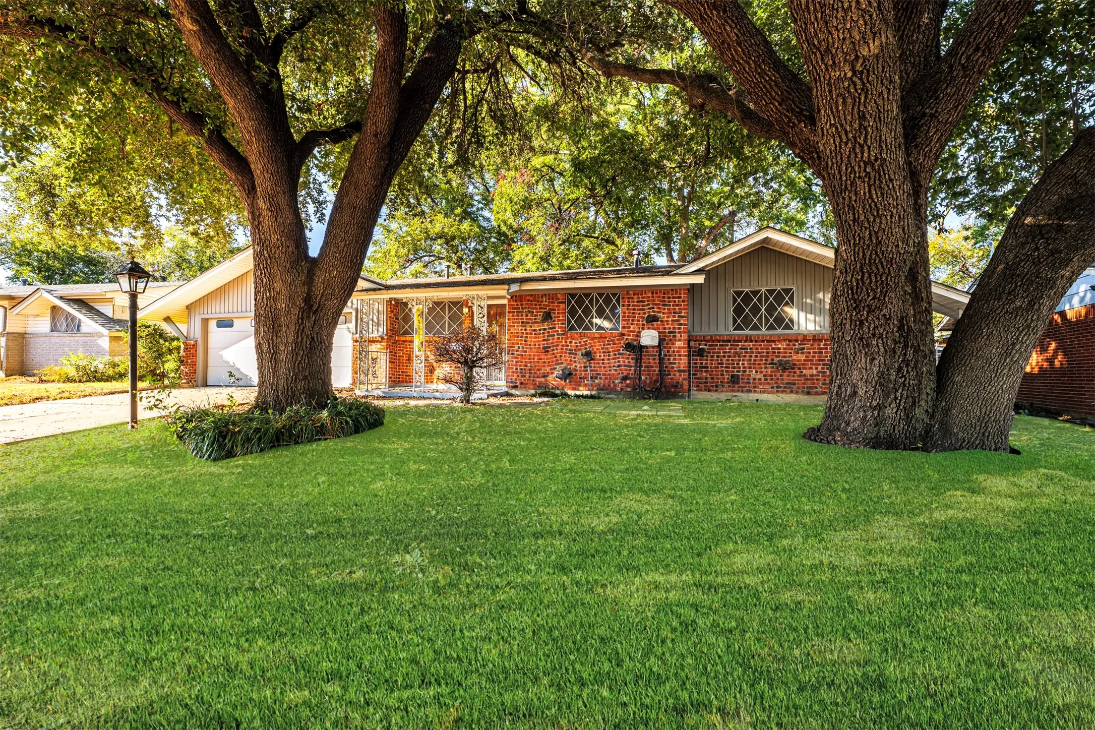 Ranch-style house with an attached garage, a front lawn, concrete driveway, and brick siding