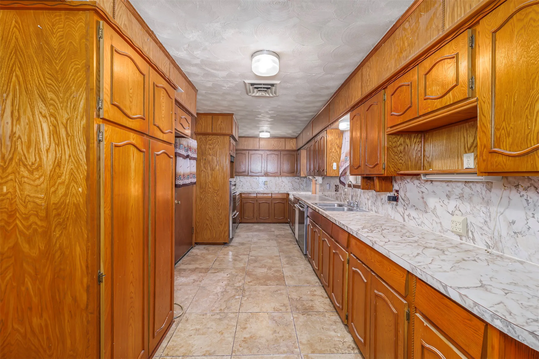 Kitchen with wood finish cabinetry, light countertops, backsplash, and a textured ceiling