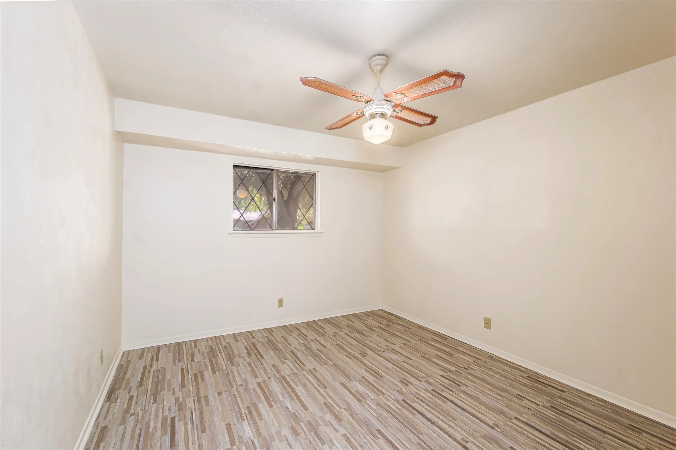 Empty room with ceiling fan and light wood-style floors