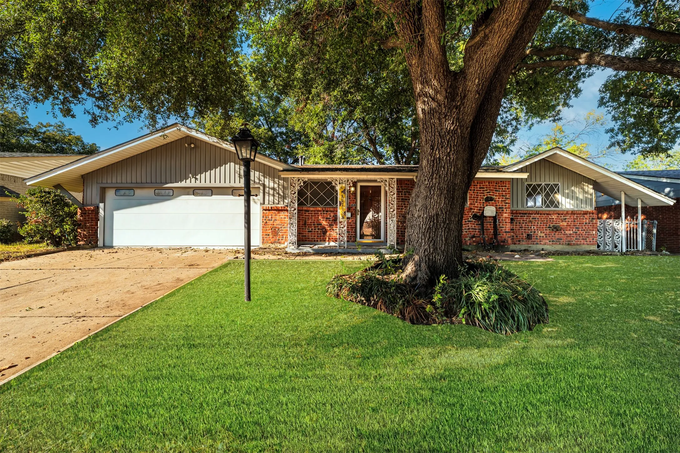 Ranch-style house featuring a garage, concrete driveway, brick siding, and a front yard