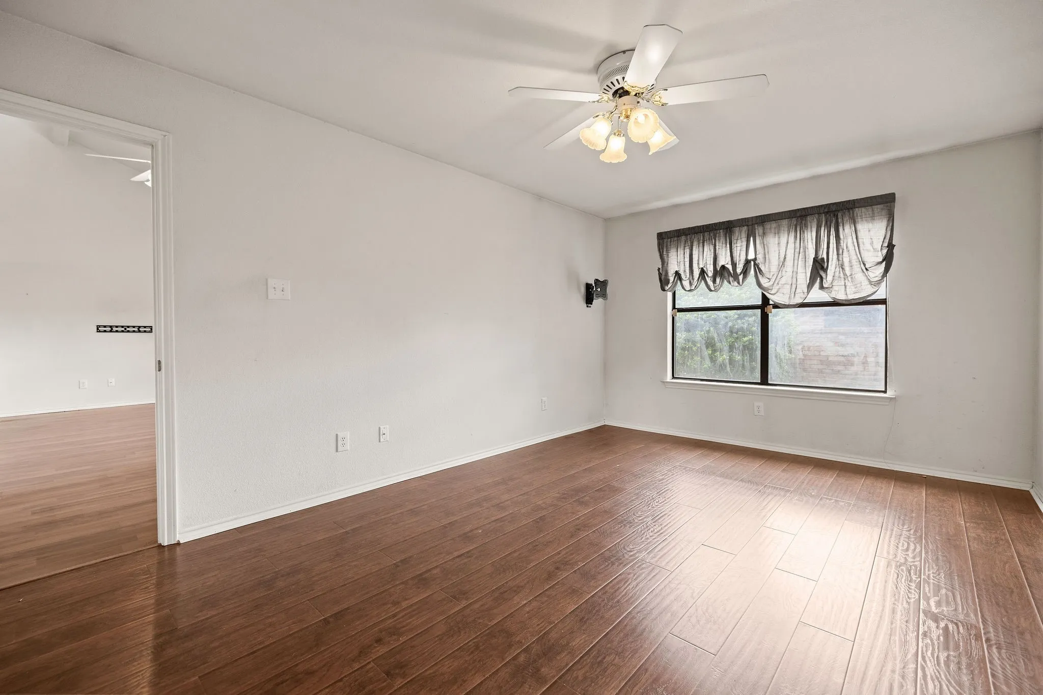 Spare room featuring a ceiling fan, wood-type flooring, and baseboards